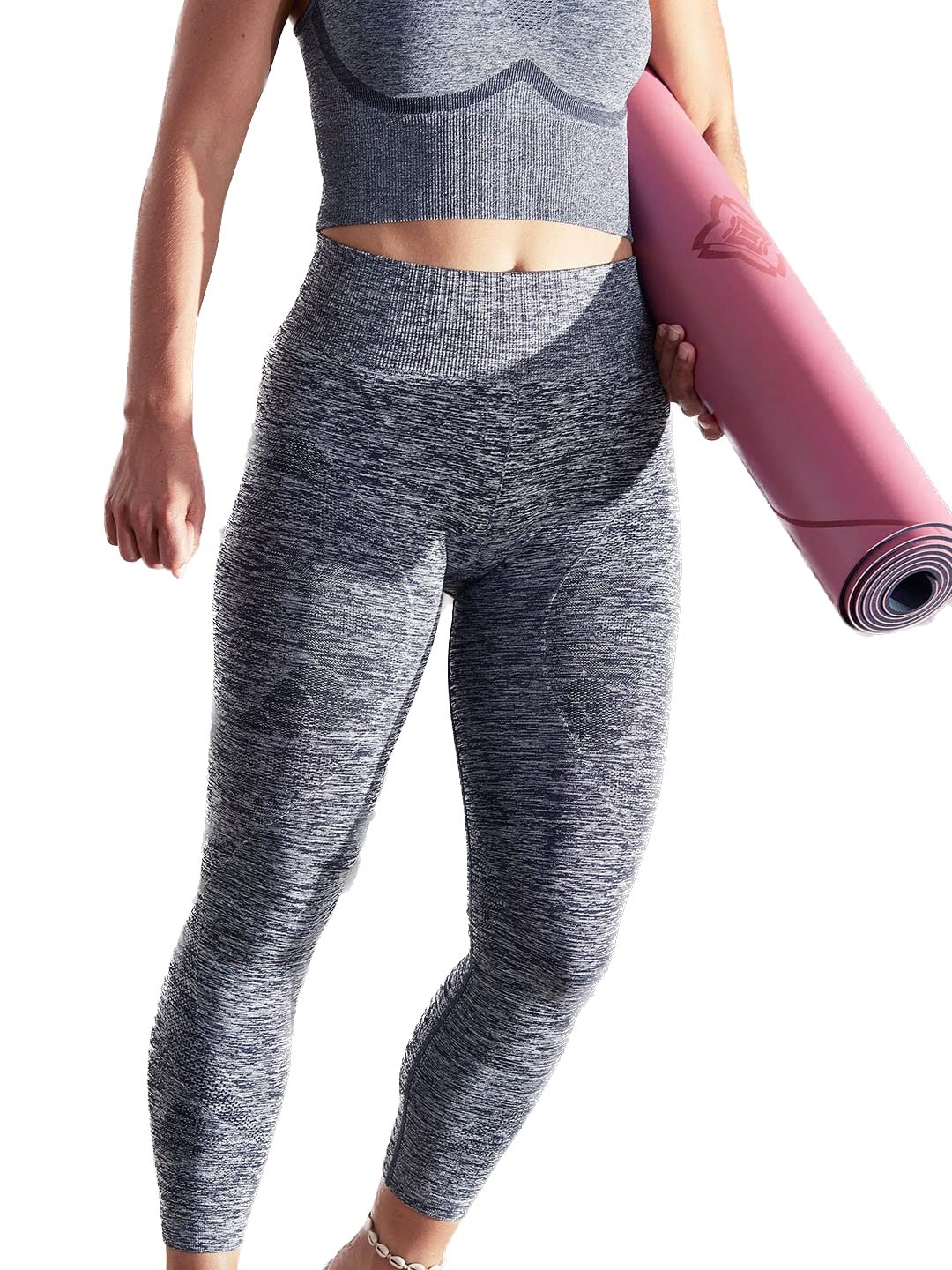 A woman wearing grey seamless yoga leggings and a matching top, holding a pink yoga mat.