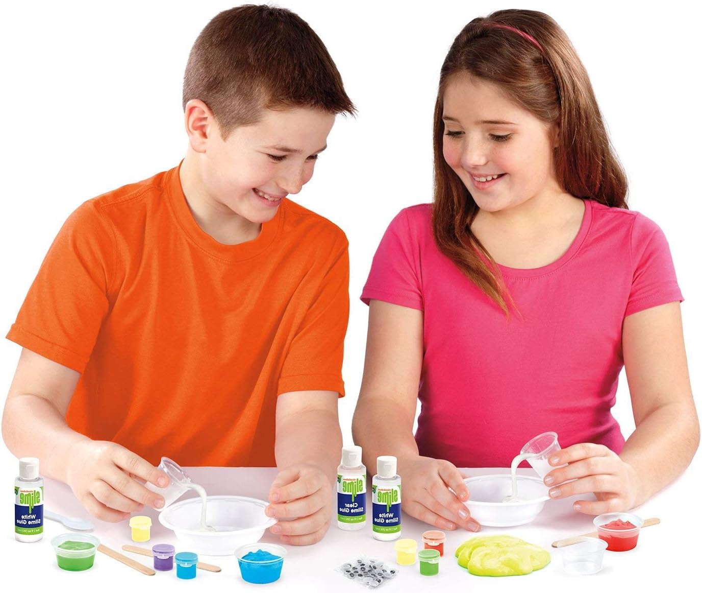 Two children, a boy and a girl, mixing ingredients in bowls to make slime, surrounded by various slime kit components.