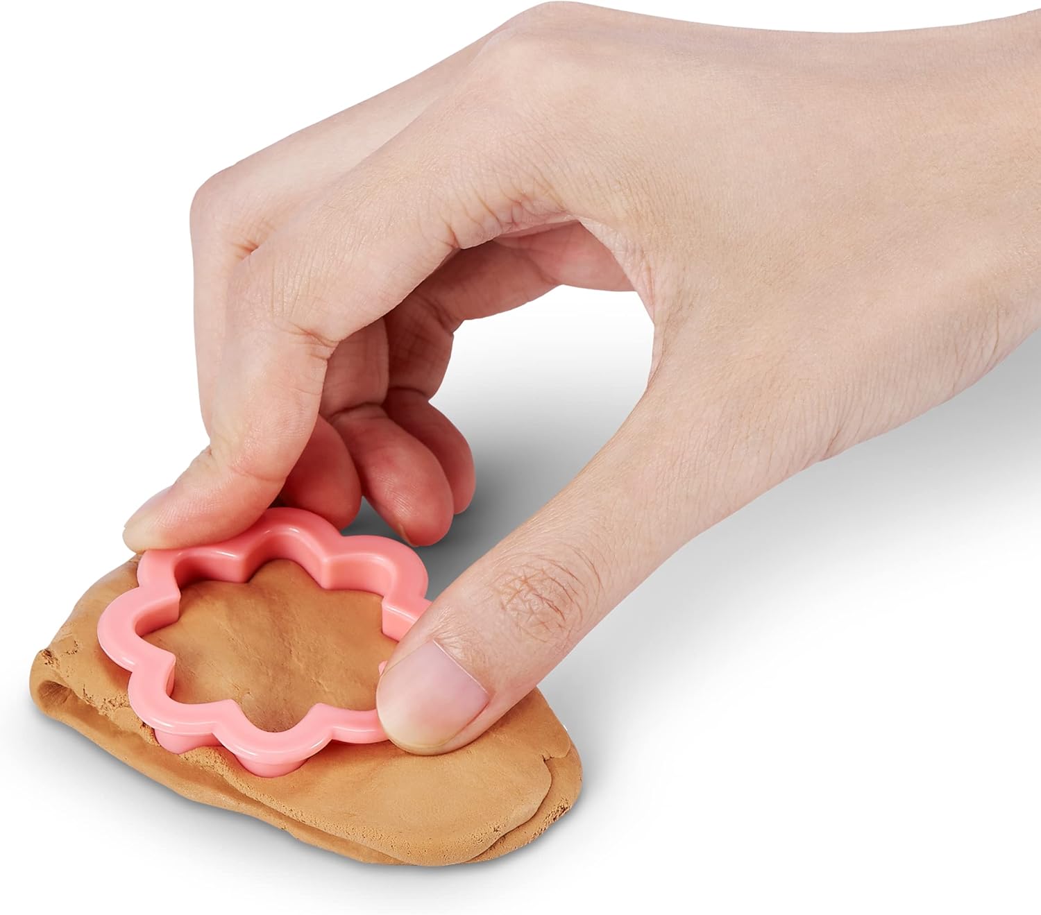 Hand using a toy dough cutter to remove excess dough from a heart shape