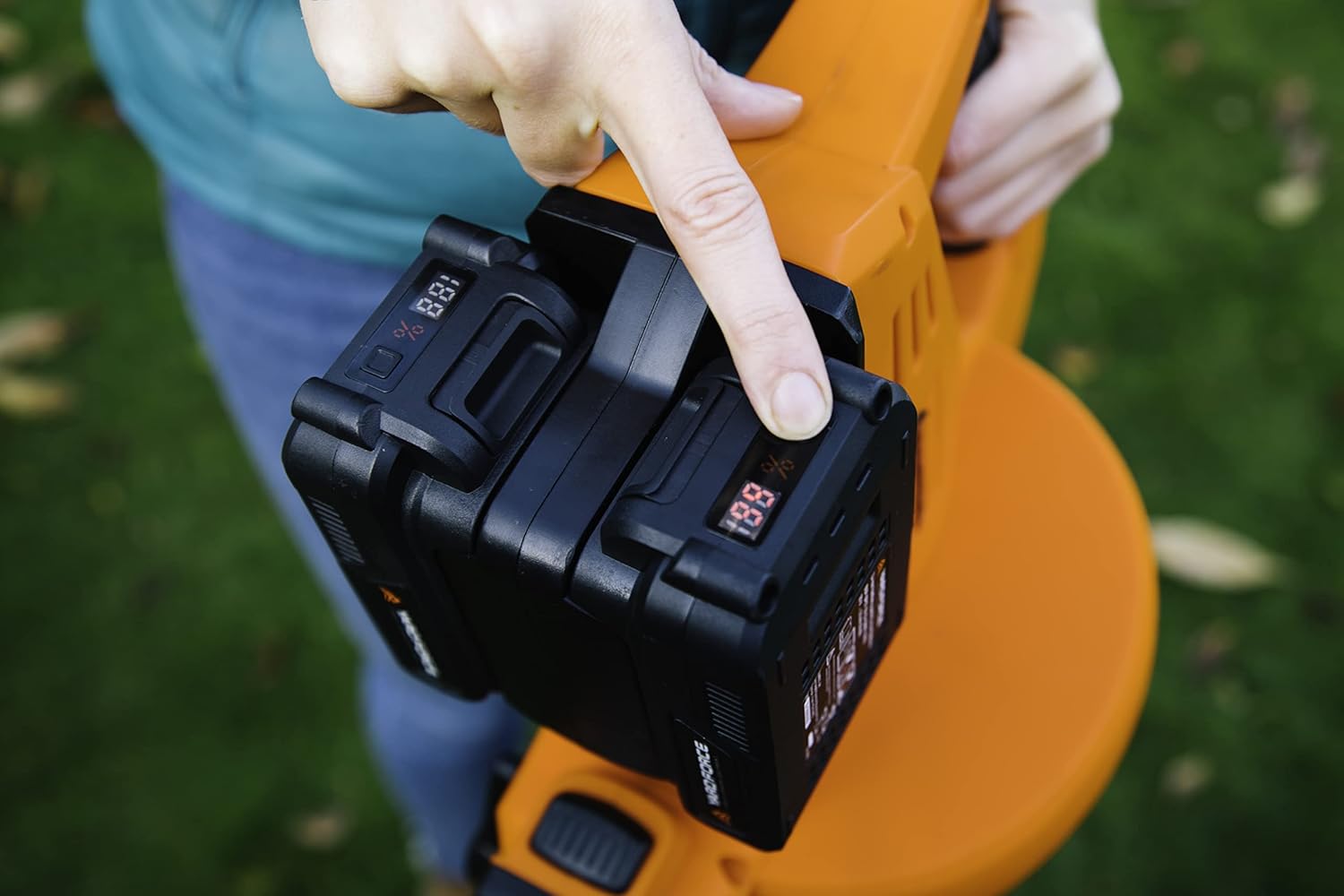 Hand pressing the battery level indicator button on a Yard Force 20V battery