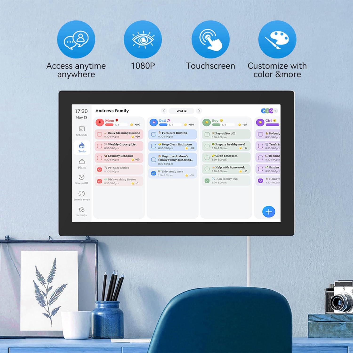 ASHATA Smart Digital Calendar mounted on a wall, displaying a family schedule with tasks assigned to different family members. Icons for access anytime, 1080P, touchscreen, and customization are shown above.