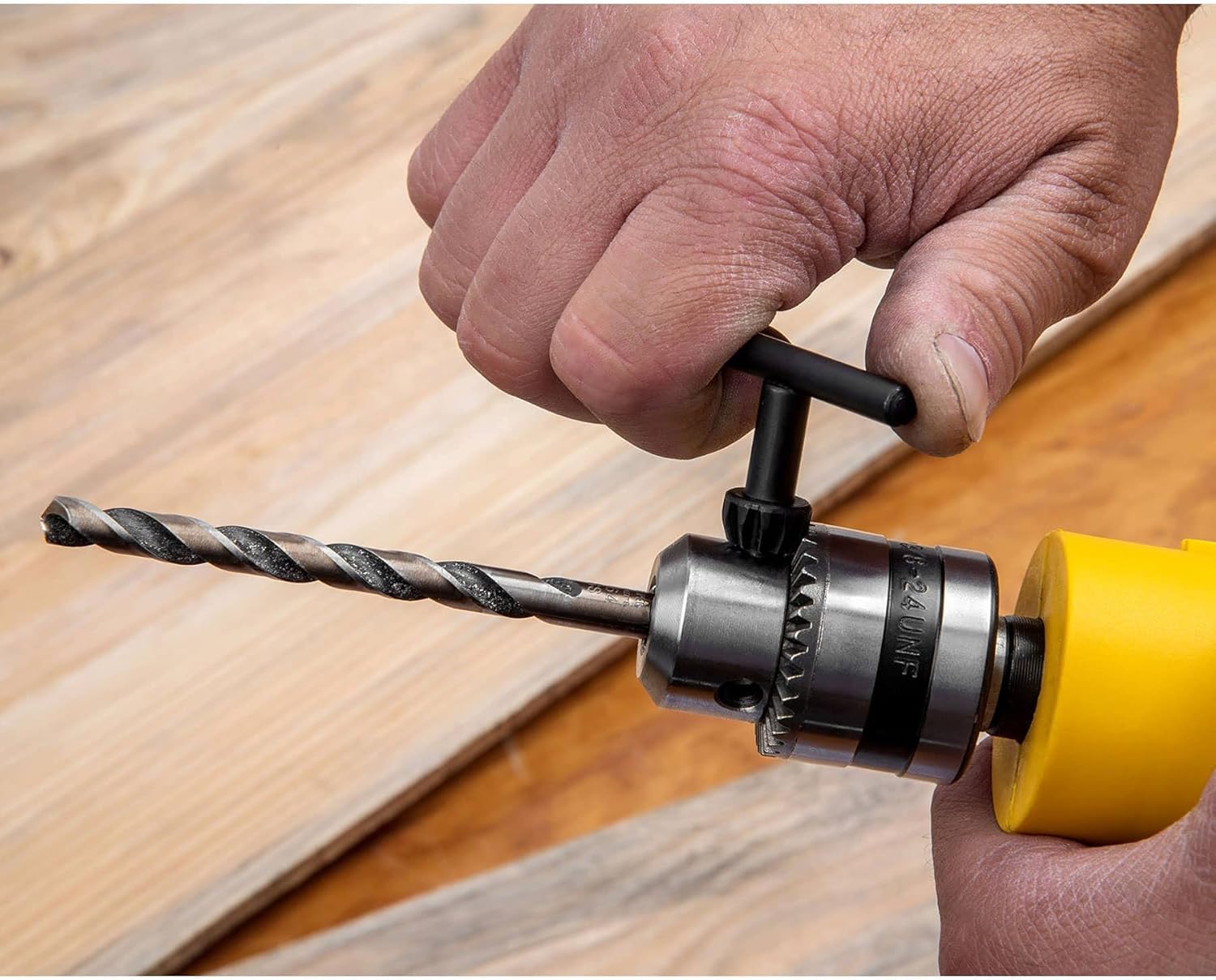 Hand using chuck key to tighten drill bit