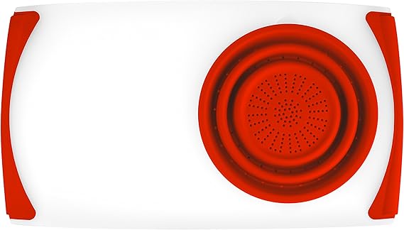 The cutting board and strainer with peppers over the sink