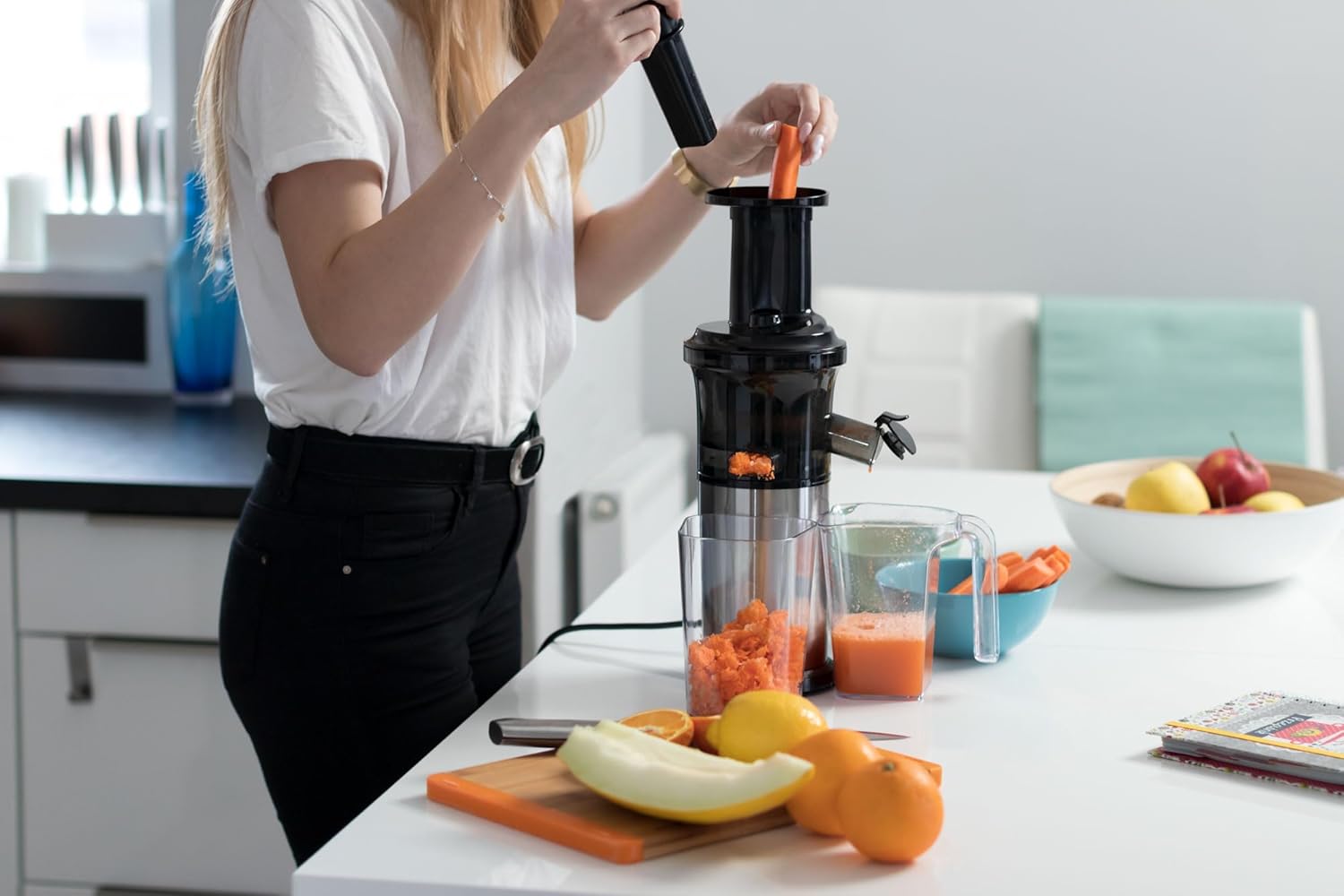 A person feeding a carrot into the Teesa TSA3228 Slow Juicer's feeding chute.