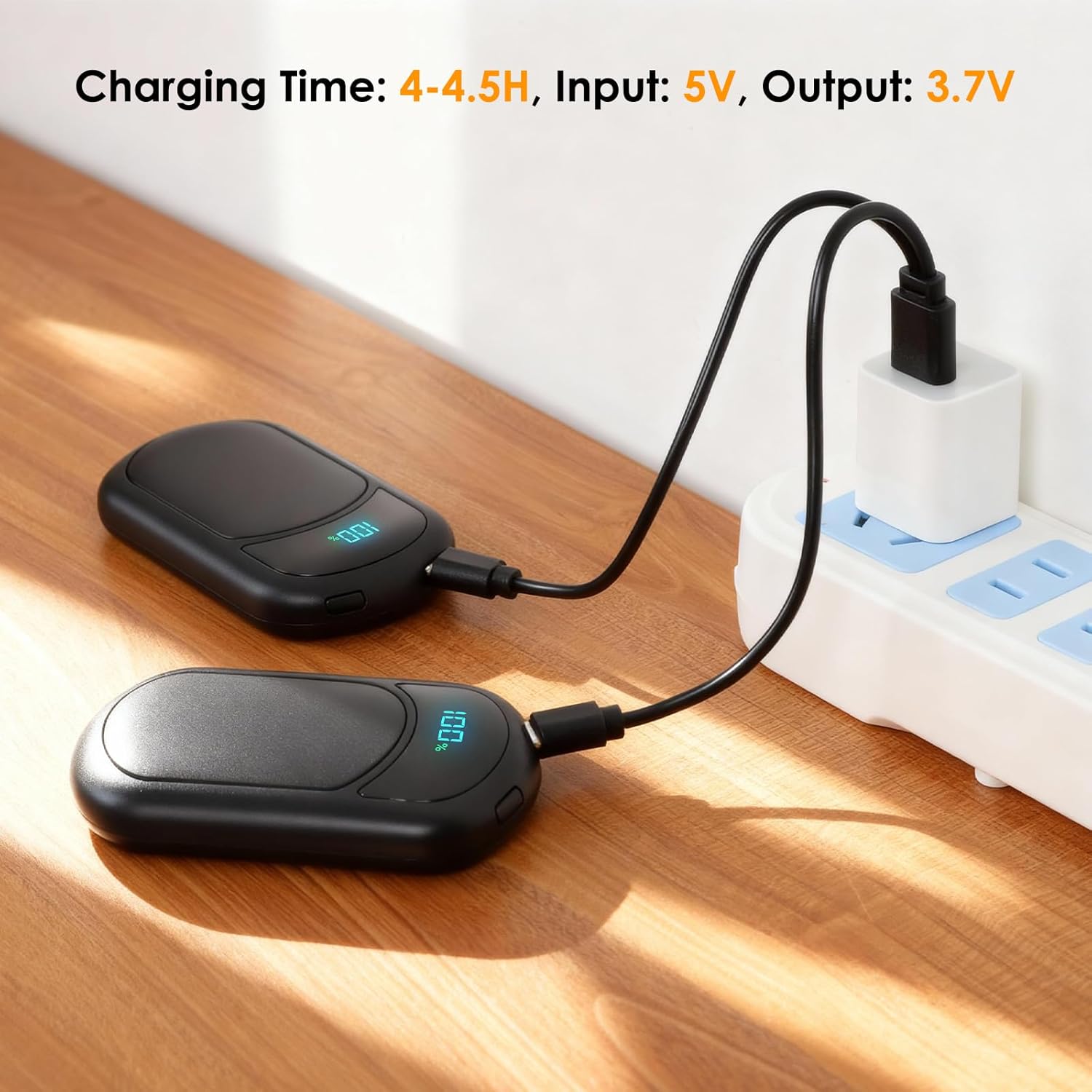 Two ropelux HW-06 hand warmers being charged via USB cables from a wall adapter.