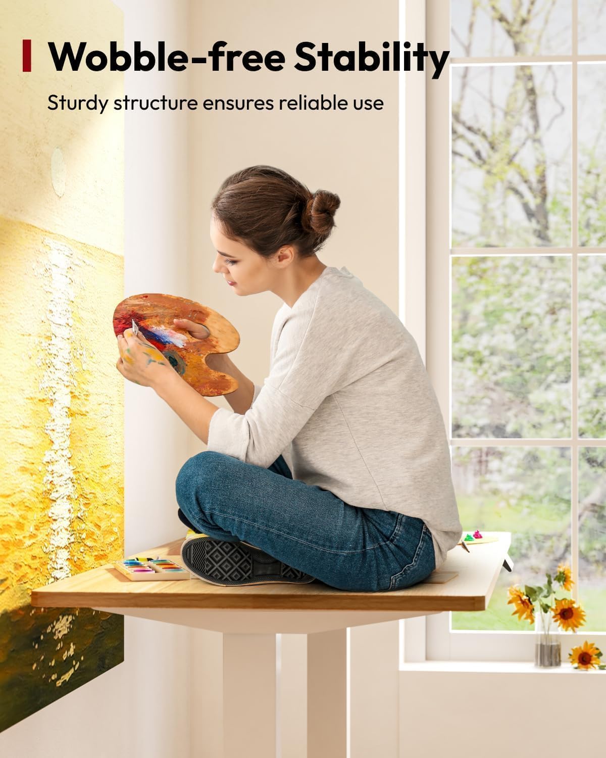 Woman sitting cross-legged on the SANODESK EP1 desktop, demonstrating its stability.