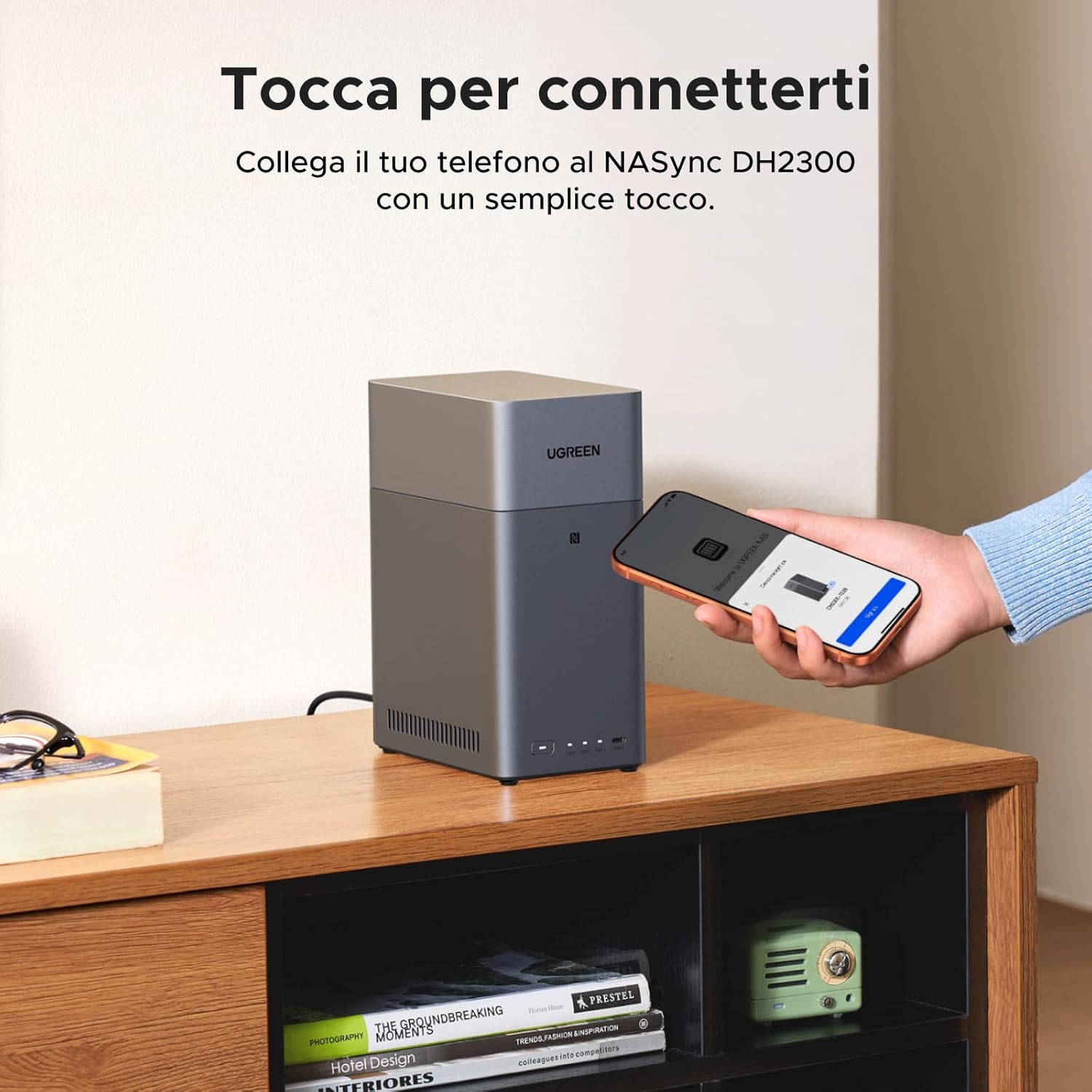 A hand holding a smartphone tapping it against the NFC area of the UGREEN NASync DH2300 for one-touch connection.