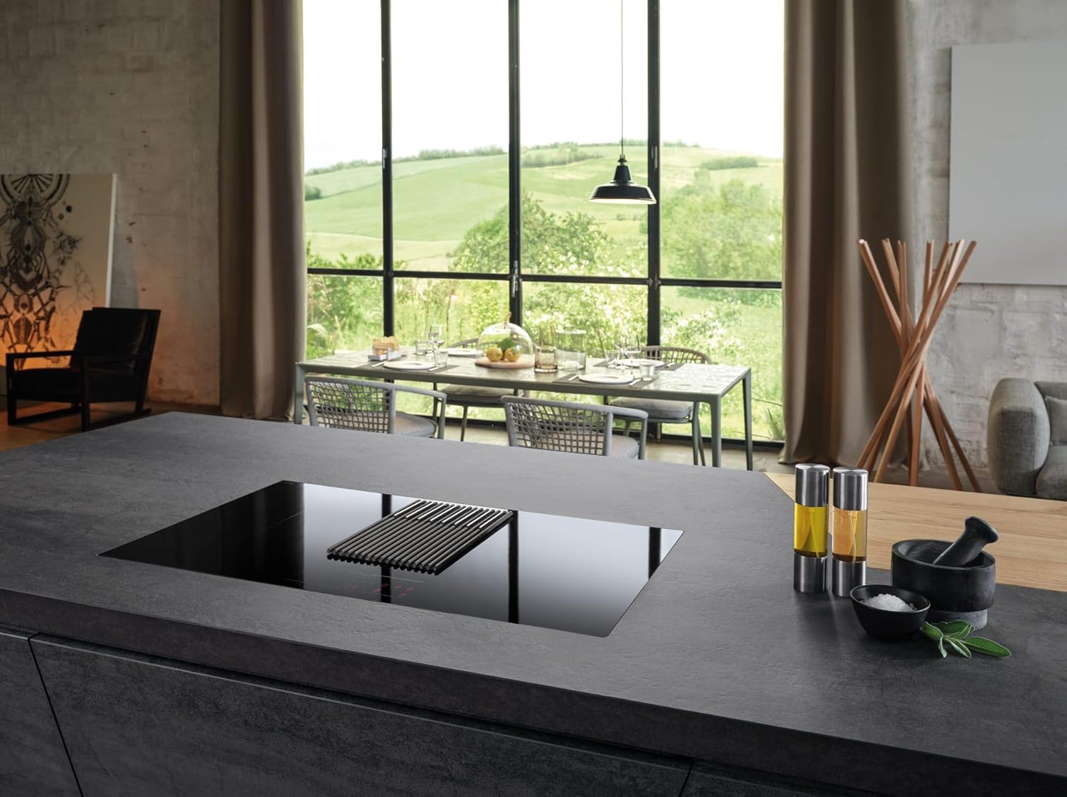 Elica NikolaTesla Libra Black induction hob integrated into a modern kitchen island, with a dining area visible in the background.