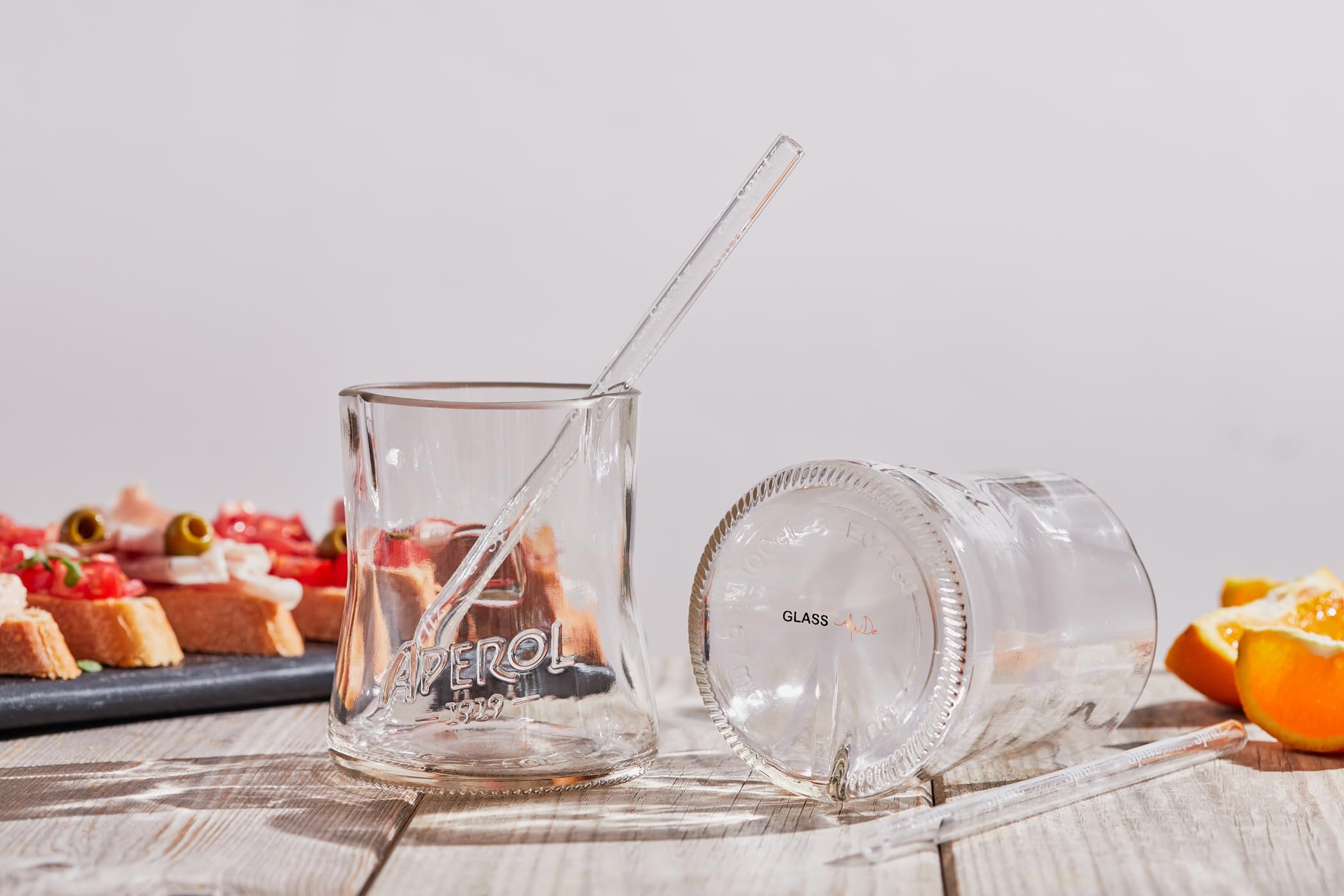 Aperol Spritz Set aus recycelten Flaschen: zwei Glaser mit kunstvoll geformten Randern und zwei Glasstronhhalme