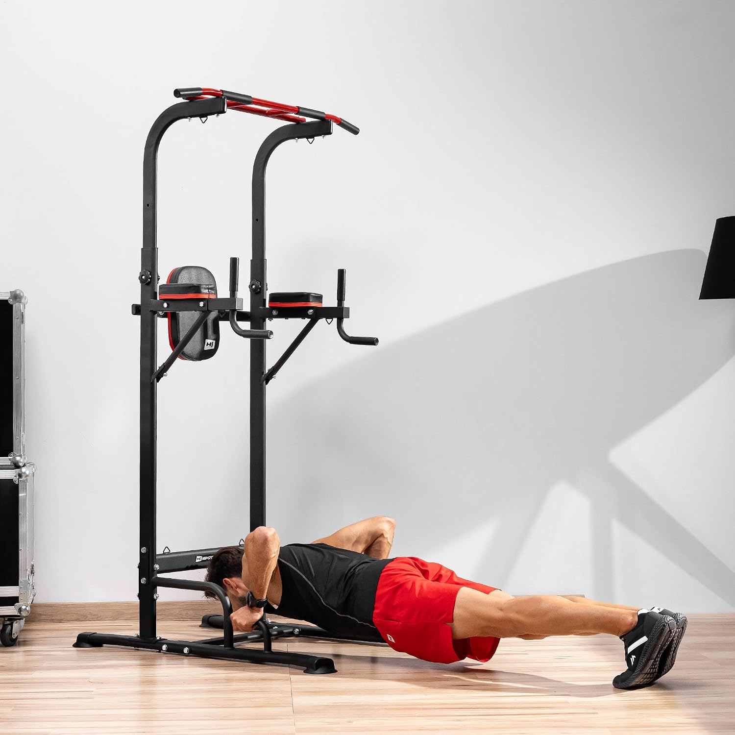 A man performing push-ups on the floor with his feet elevated on the base of the Hop-Sport Power Tower.