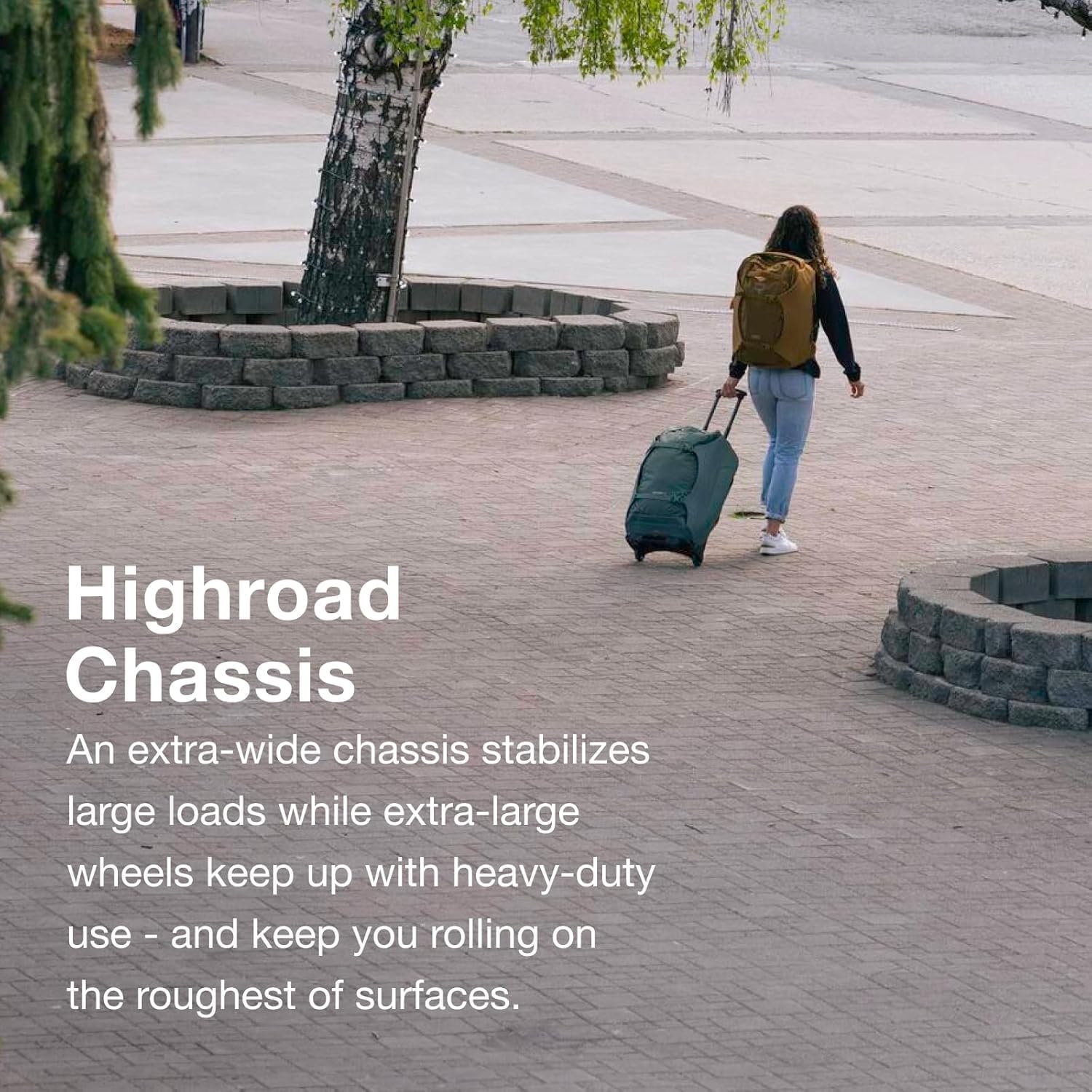 Woman pulling Osprey Sojourn Wheeled Travel Pack on a paved surface, highlighting the HighRoad Chassis.