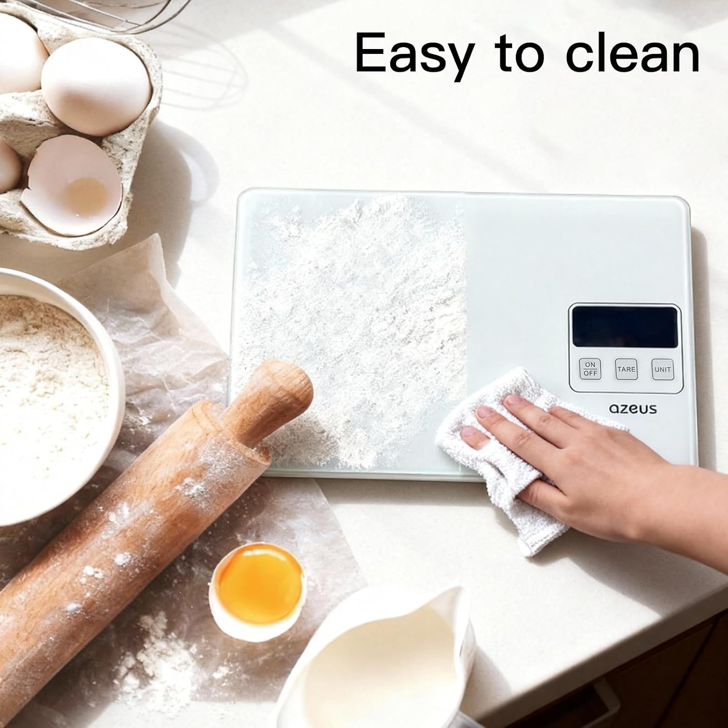 A hand wiping the surface of the AZEUS Digital Kitchen Scale with a cloth, surrounded by baking ingredients