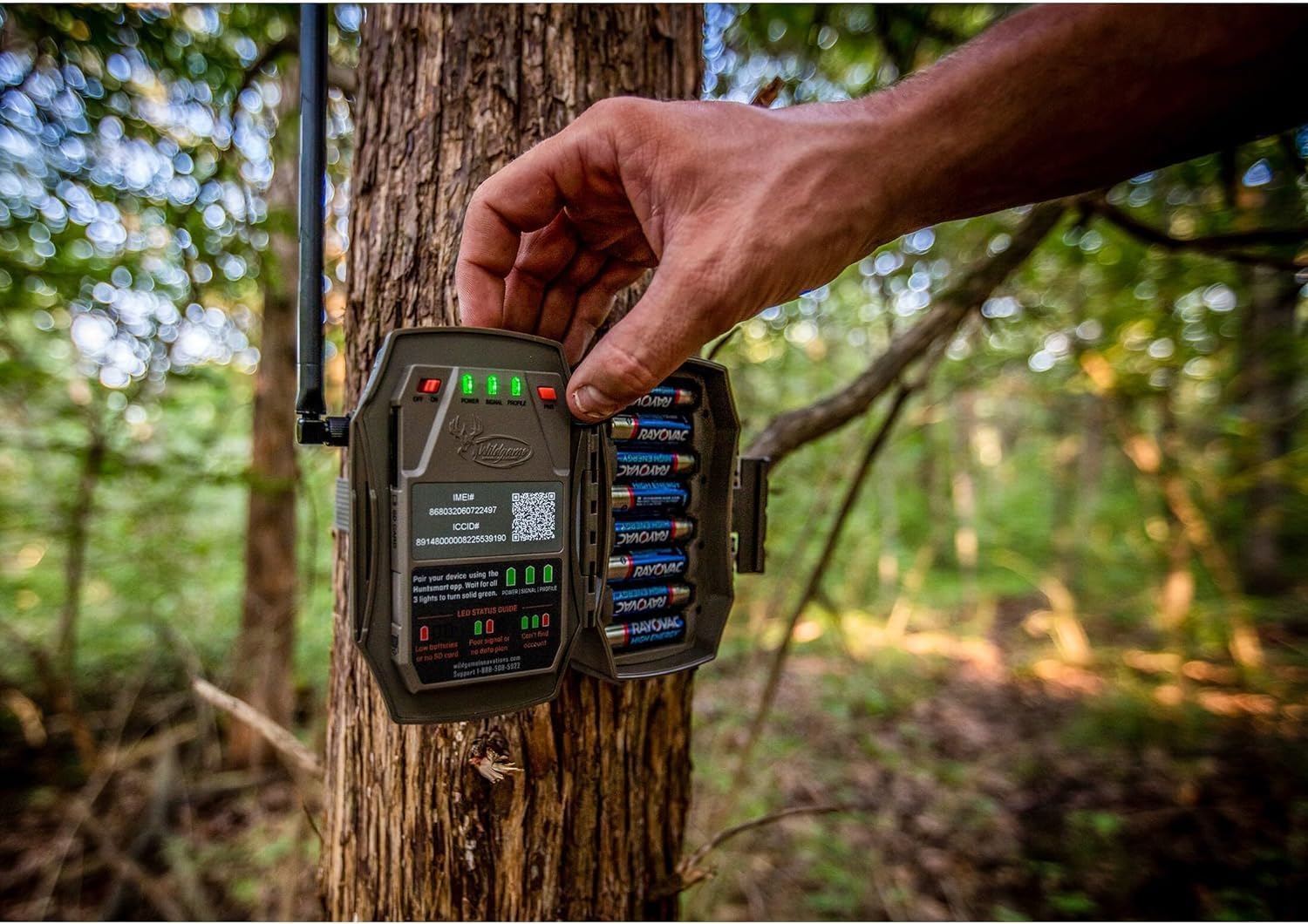 Hand installing AA batteries into the Wildgame Innovations Terra Xt Cellular Camera