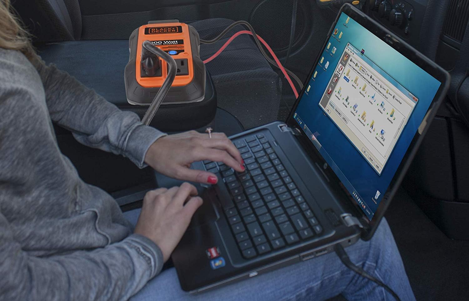 Donna che utilizza un computer portatile alimentato dall'inverter BLACK+DECKER da 500 Watt all'interno di un'auto