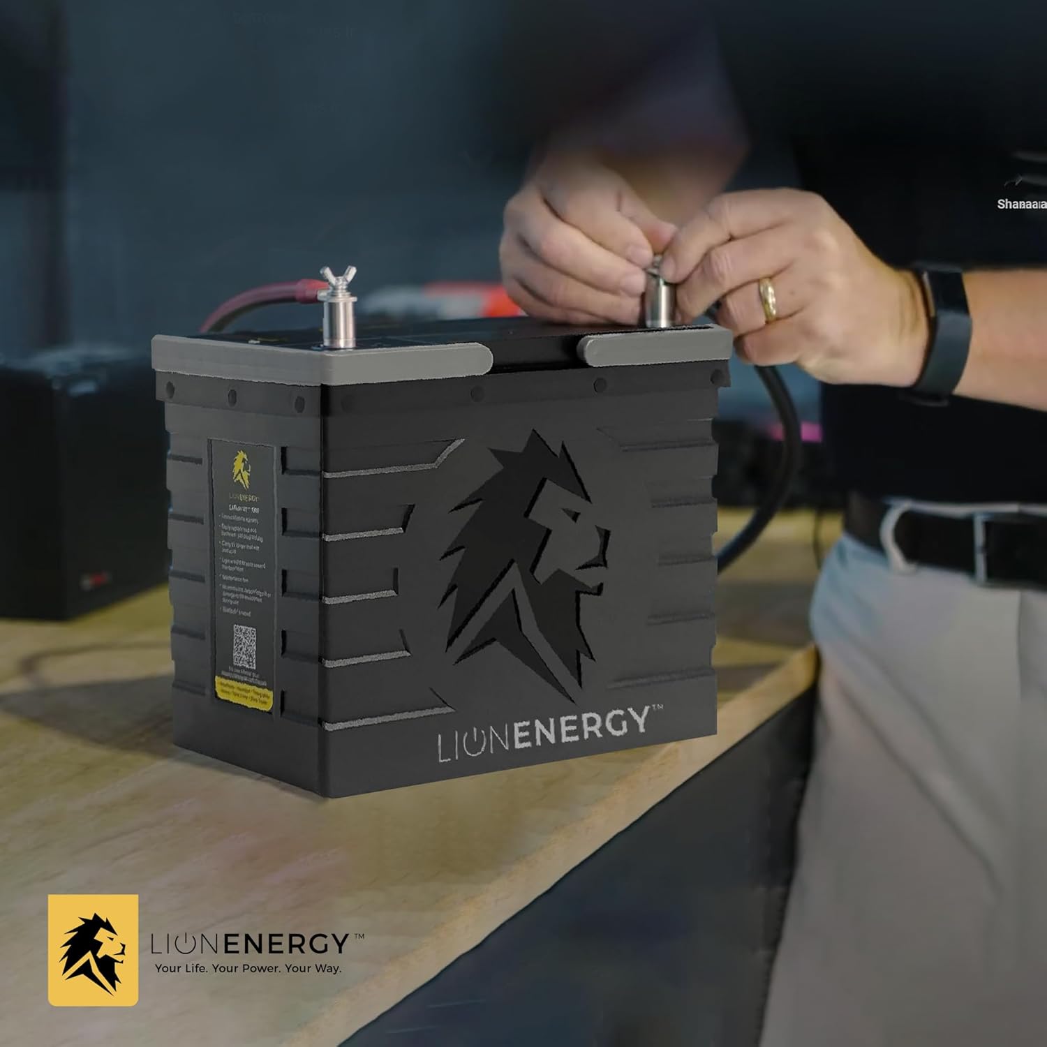 Hands connecting wires to battery terminals