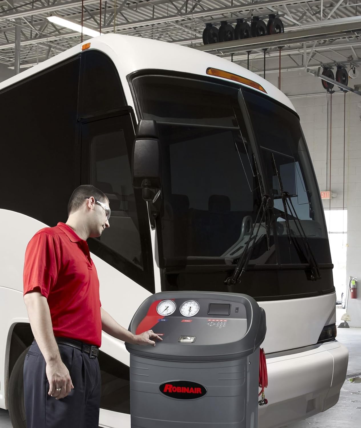 Technician operating Robinair 34888HD next to a bus