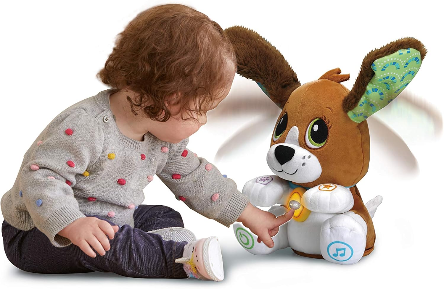 A young child sitting on the floor, reaching out to press a button on the VTech Fido plush dog's paw.