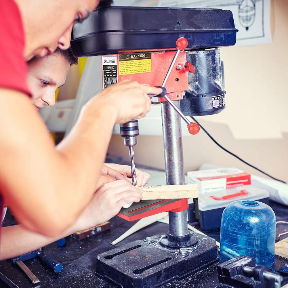 Two individuals operating the bench drill on a wooden workpiece