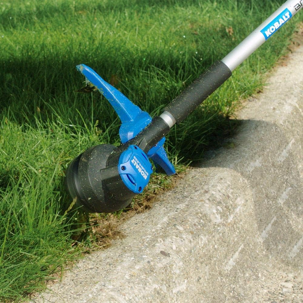 Close-up of a string trimmer cutting grass along a concrete edge