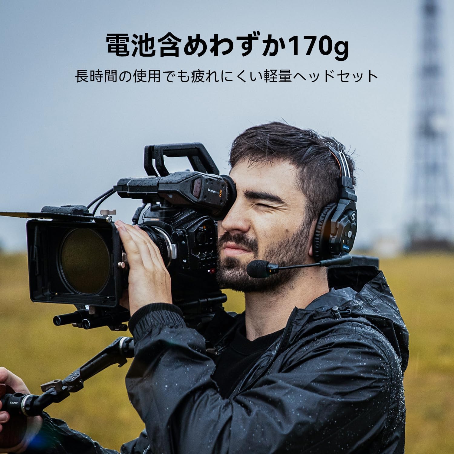 屋外で業務用カメラを構える男性カメラマン。耳には「Hollyland Solidcom C1 Pro」ワイヤレスヘッドセットを装着しており、上部には「電池含めわずか170g」「長時間の使用でも疲れにくい軽量ヘッドセット」という日本語のテキストが記載されている。