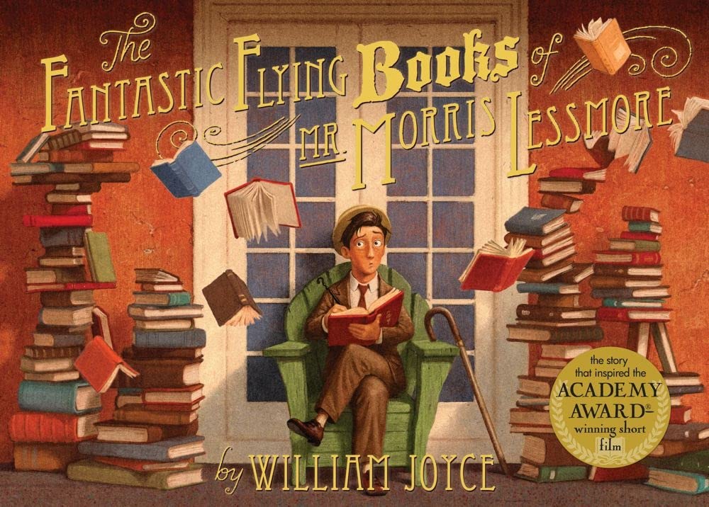Book cover of "The Fantastic Flying Books Of Mr. Morris Lessmore" by William Joyce, featuring a light-skinned man seated in a green wooden chair in front of a large paned window and holding an open book in his lap; surrounding him are large piles of books and several books flying through the air.