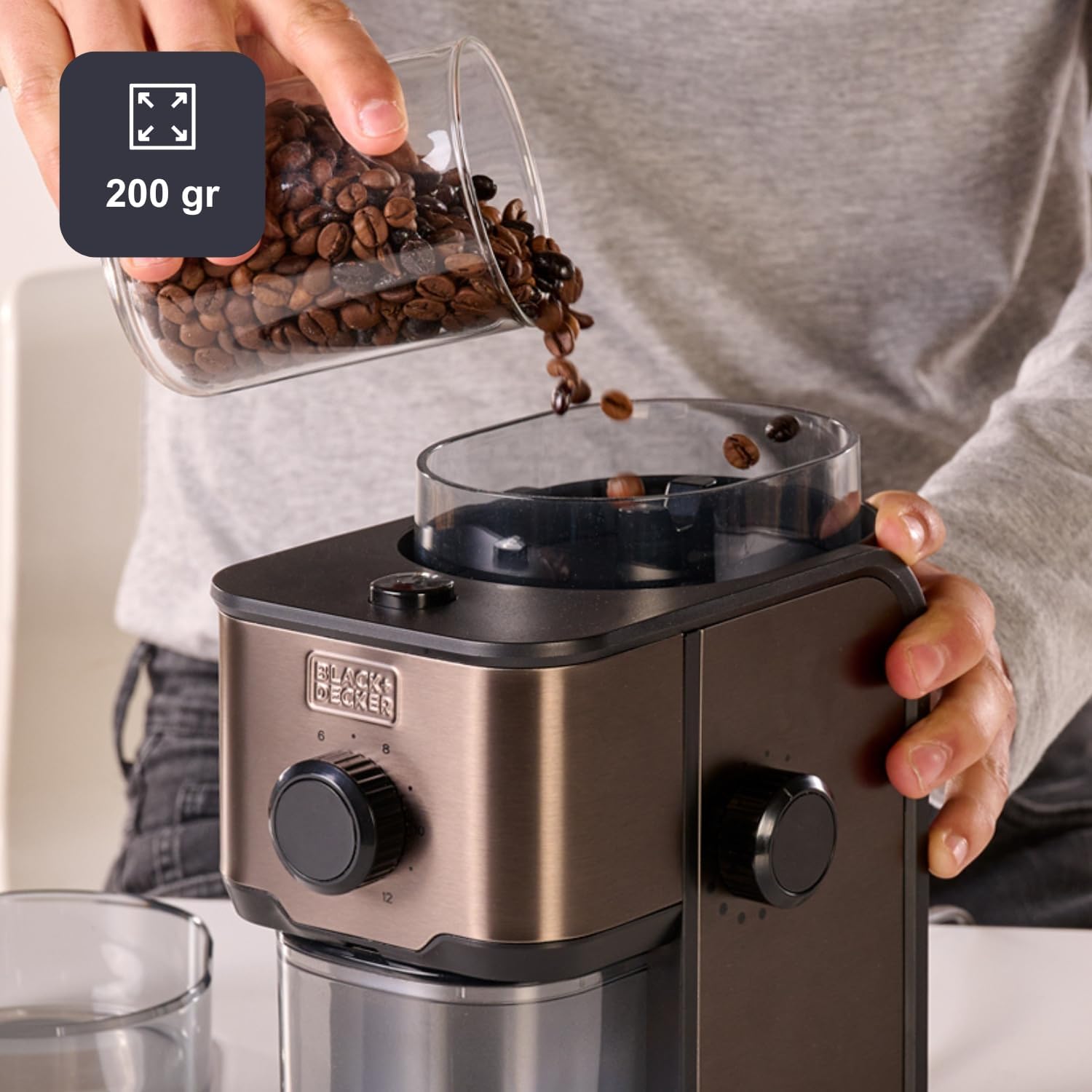 Person pouring coffee beans into the 200g reservoir of the Black+Decker coffee grinder