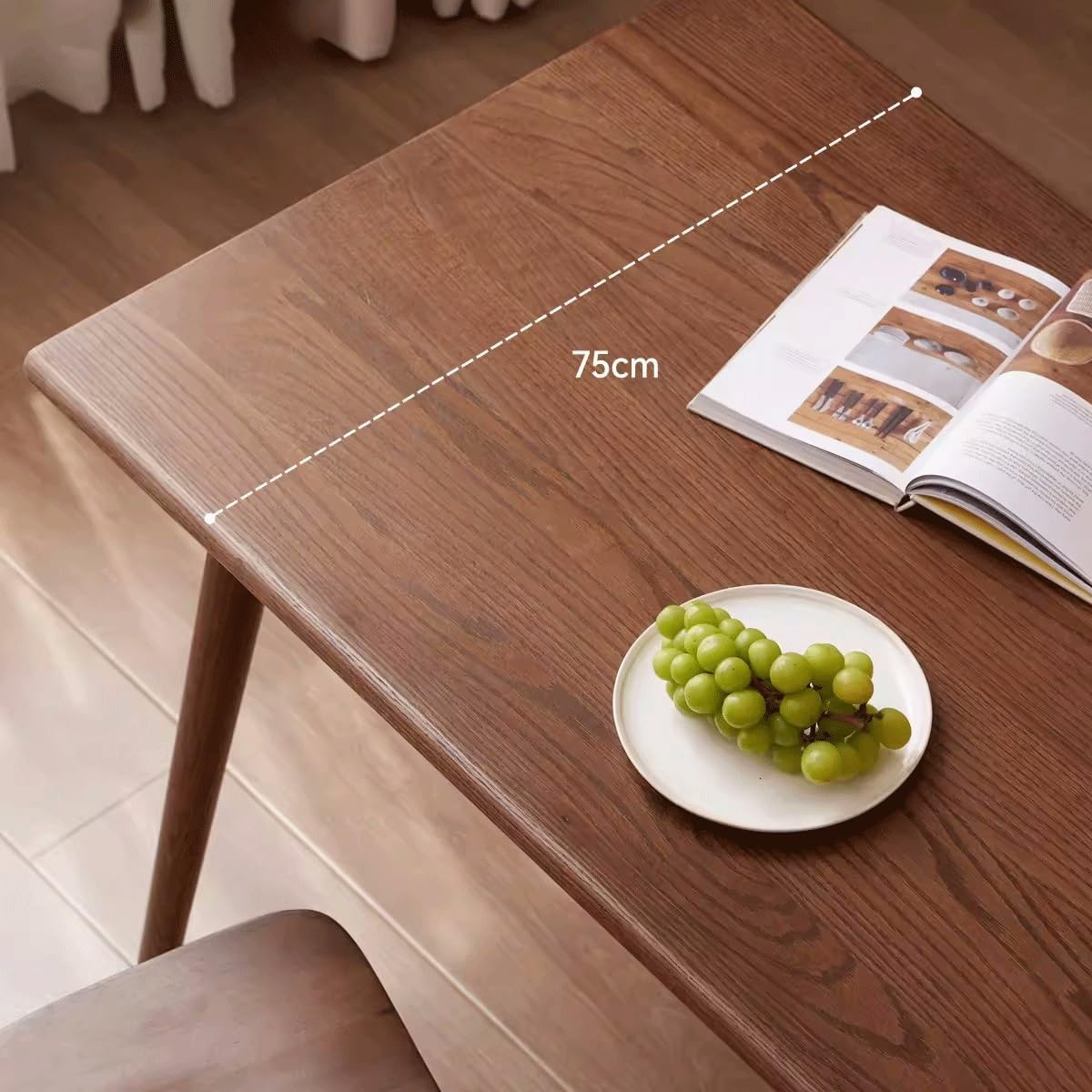 Top-down view of the dining table surface with a plate of grapes and an open book, showing the 75cm width.