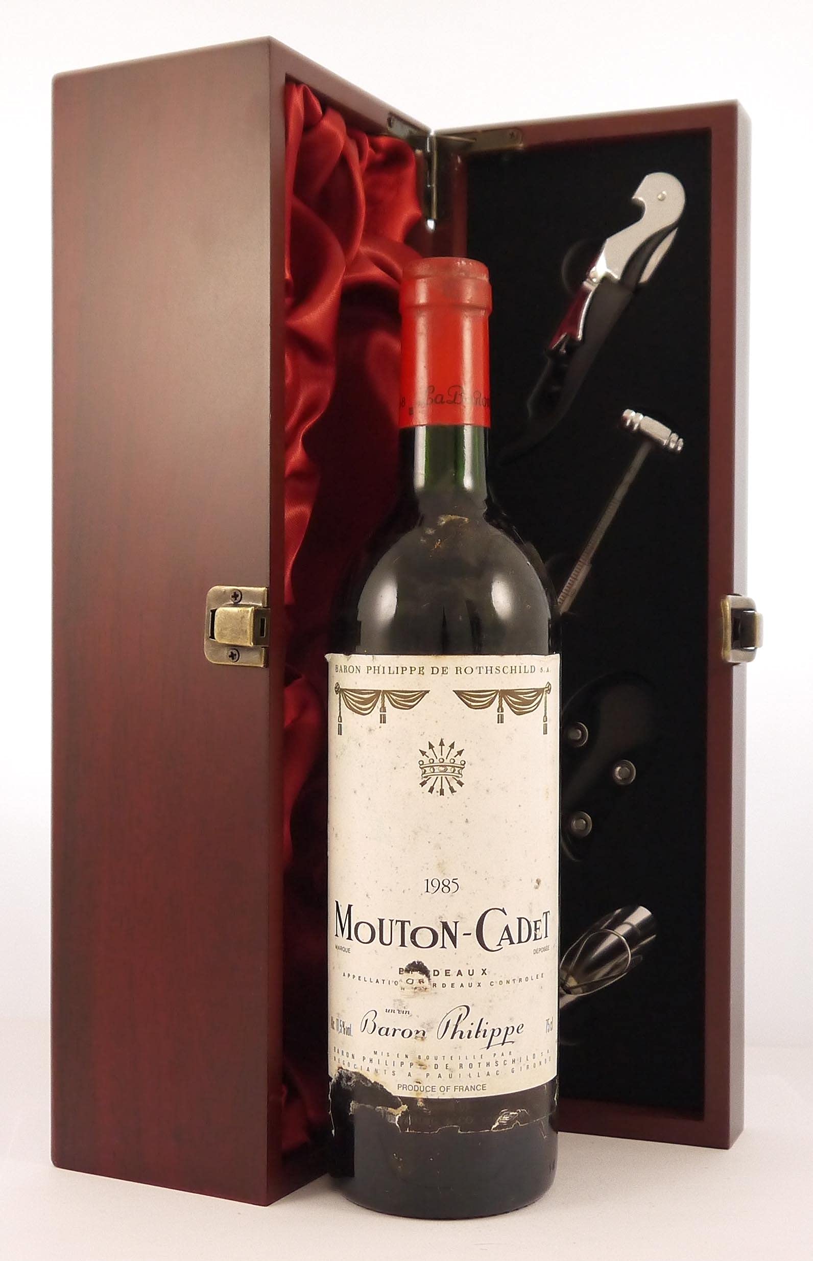Mouton Cadet 1985 Bordeaux vintage wine in a silk lined wooden box with four wine accessories, 1 x 750ml