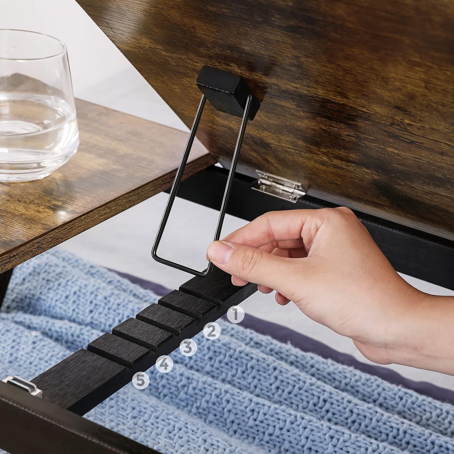 Close-up of a hand adjusting the tilt mechanism of the laptop desk, showing the five angle settings.