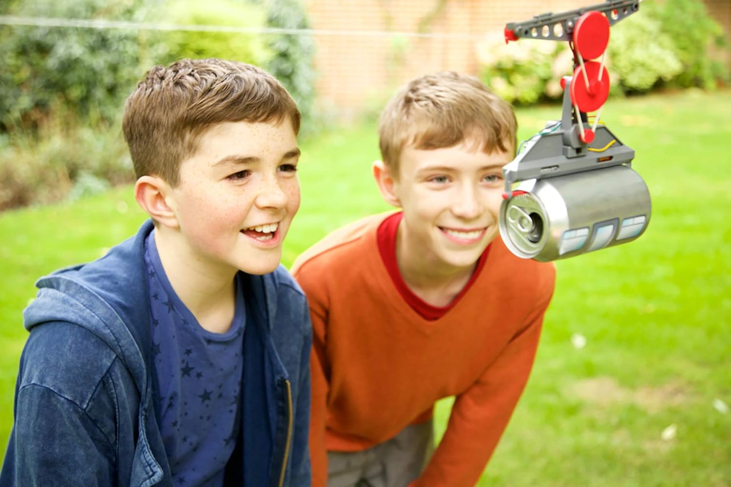 Two children observing the 4M KidzRobotix Tin Can Cable Car operating indoors on a string.
