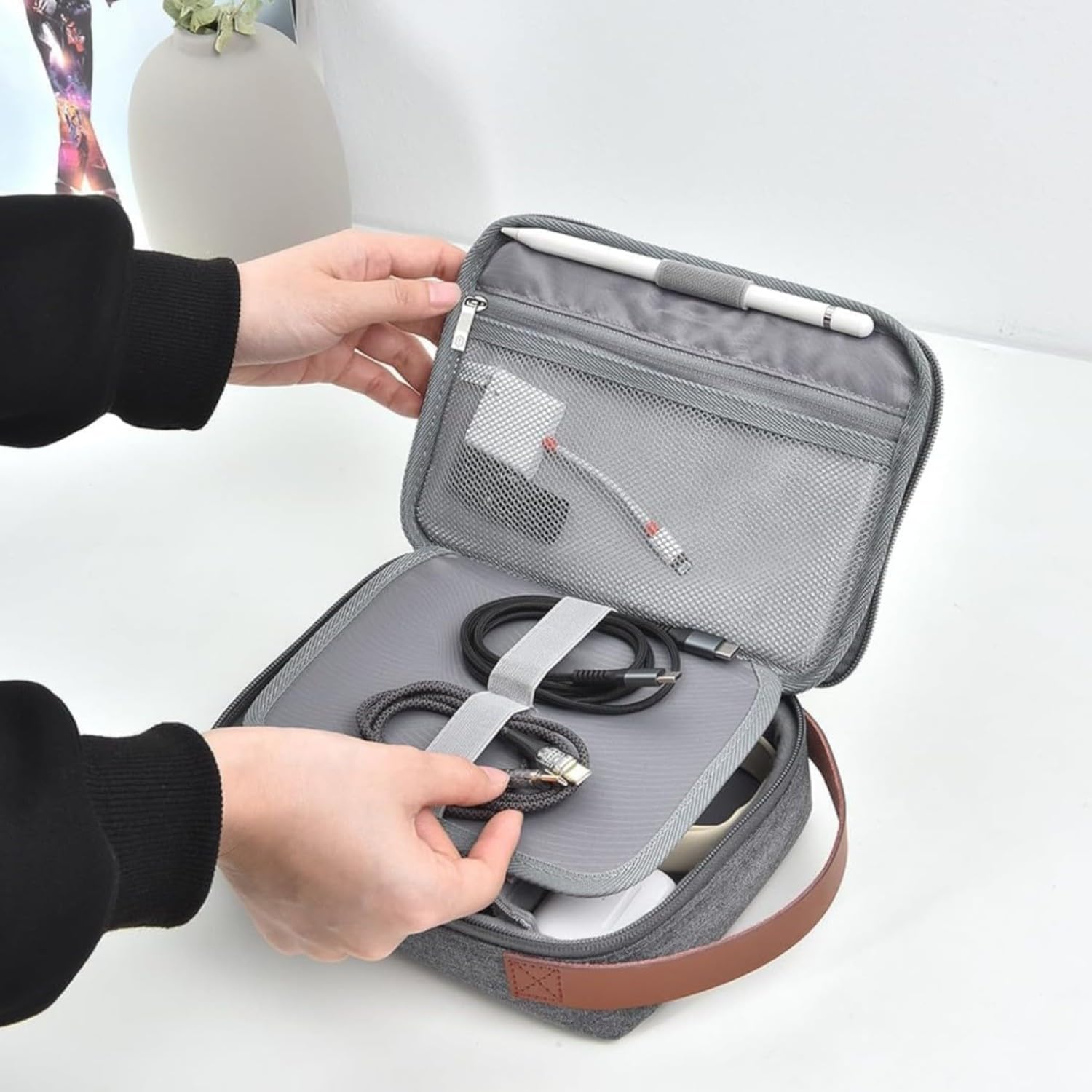 A hand pouring water onto the WIWU Tech Minimalist Organizer Pouch, demonstrating its water-resistant exterior fabric.