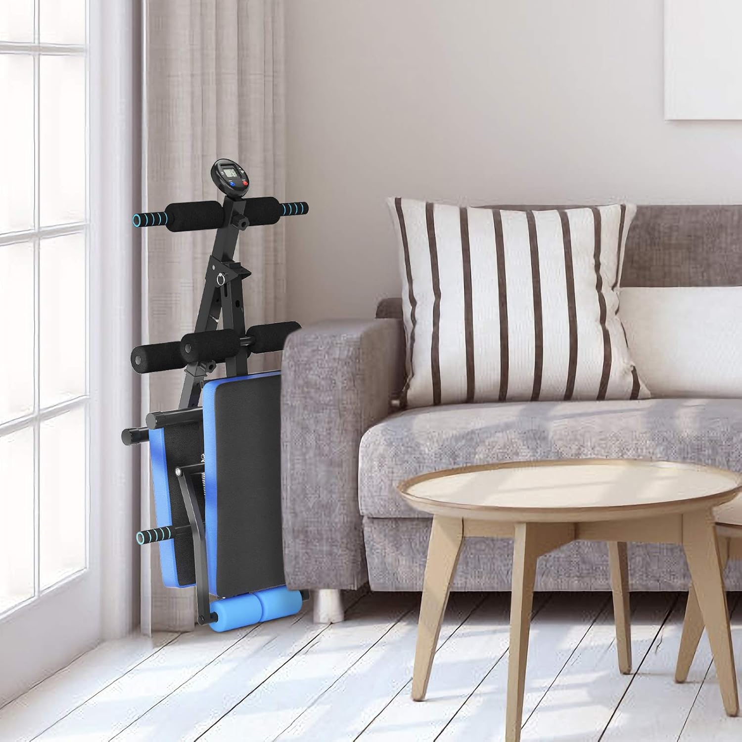 مقعد الجلوس القابل للطي من كوستواي موضوع بشكل عمودي بجوار أريكة في غرفة المعيشة، مما يدل على تصميمه الموفر للمساحة.