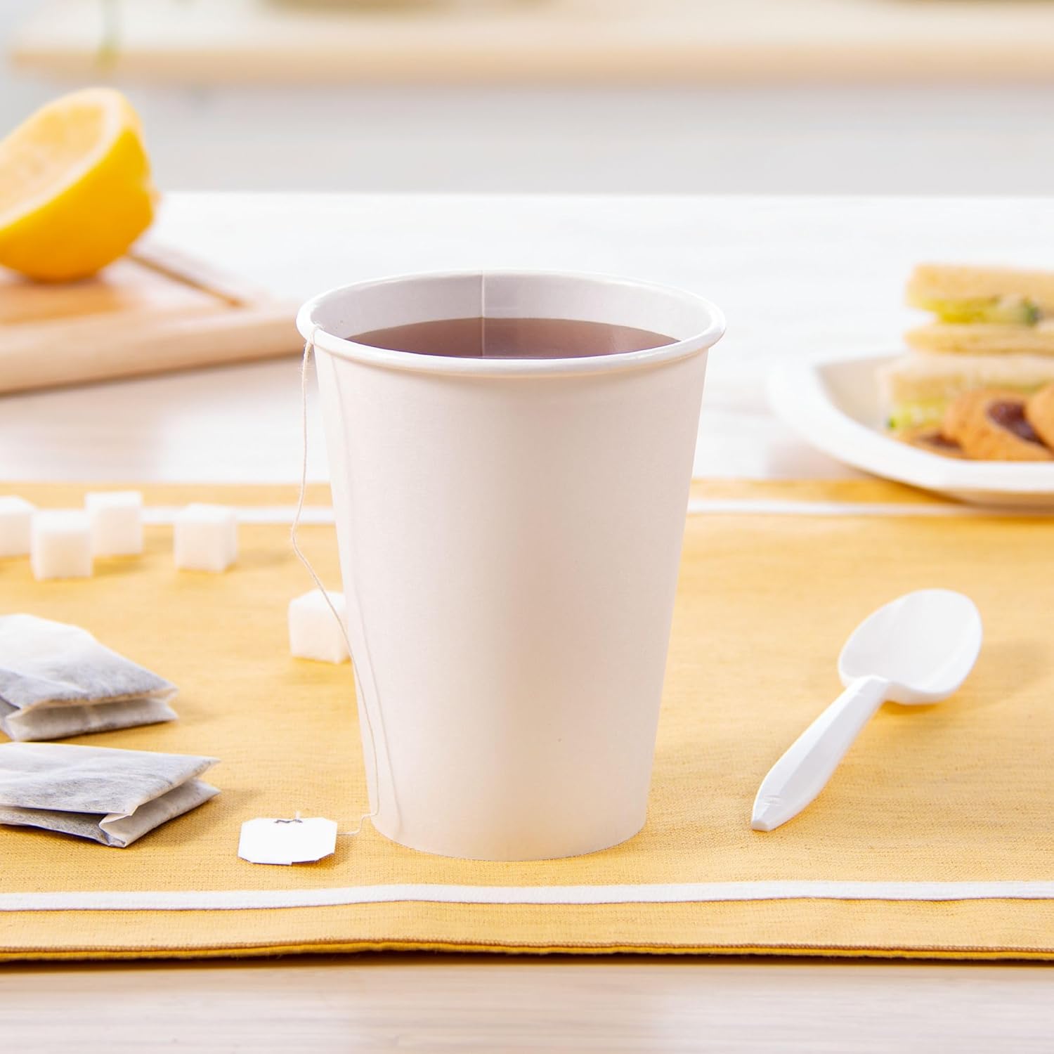 SOLO 12 oz White Paper Hot Cup filled with tea, alongside sugar cubes and a spoon.