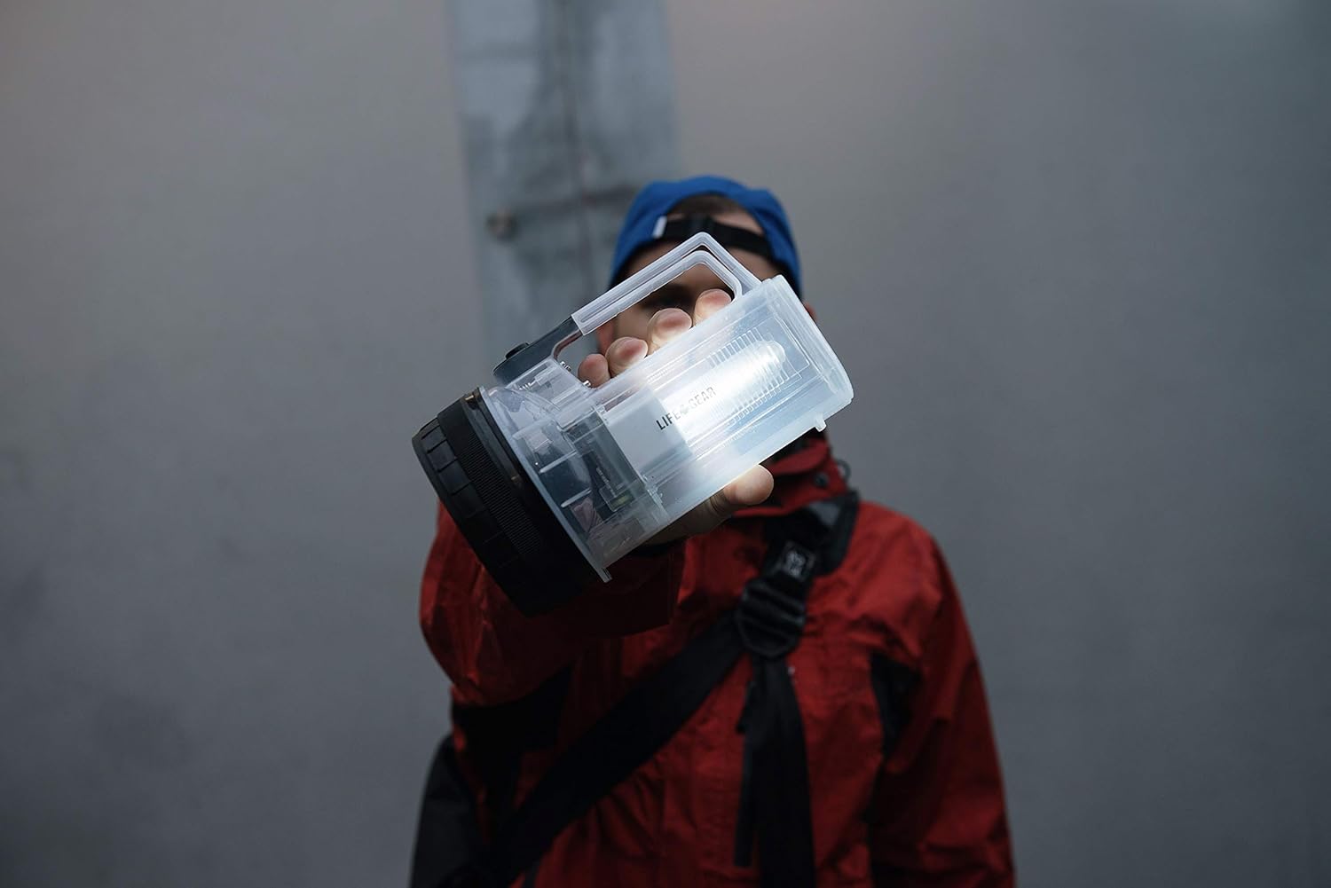 Person holding the Life Gear flashlight outdoors, demonstrating its portability and bright light.
