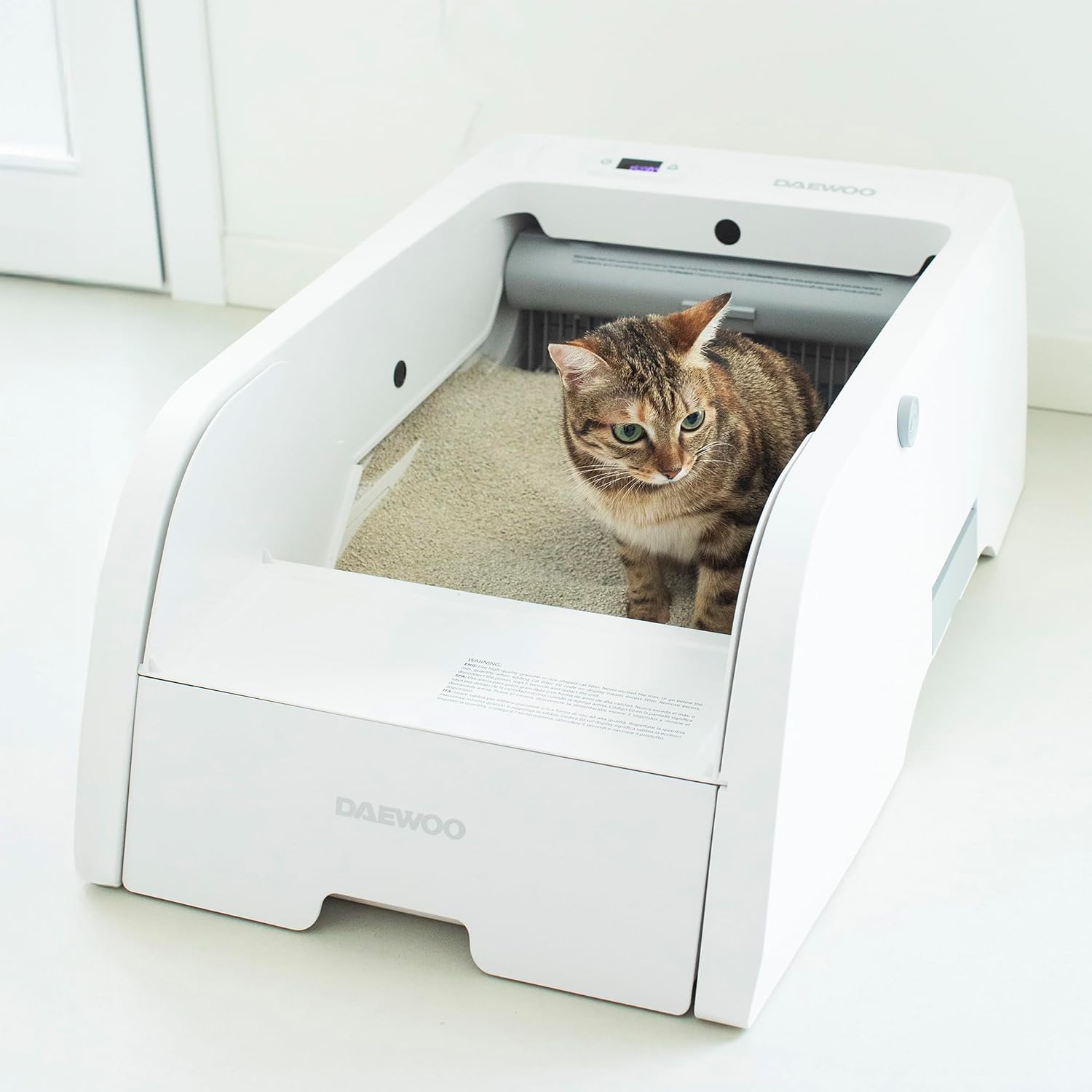 A cat sitting inside the Daewoo Automatic Cat Litter Box, demonstrating its use.