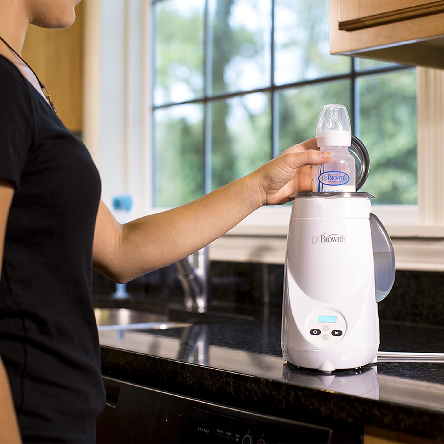 Hand placing a baby bottle into the warmer