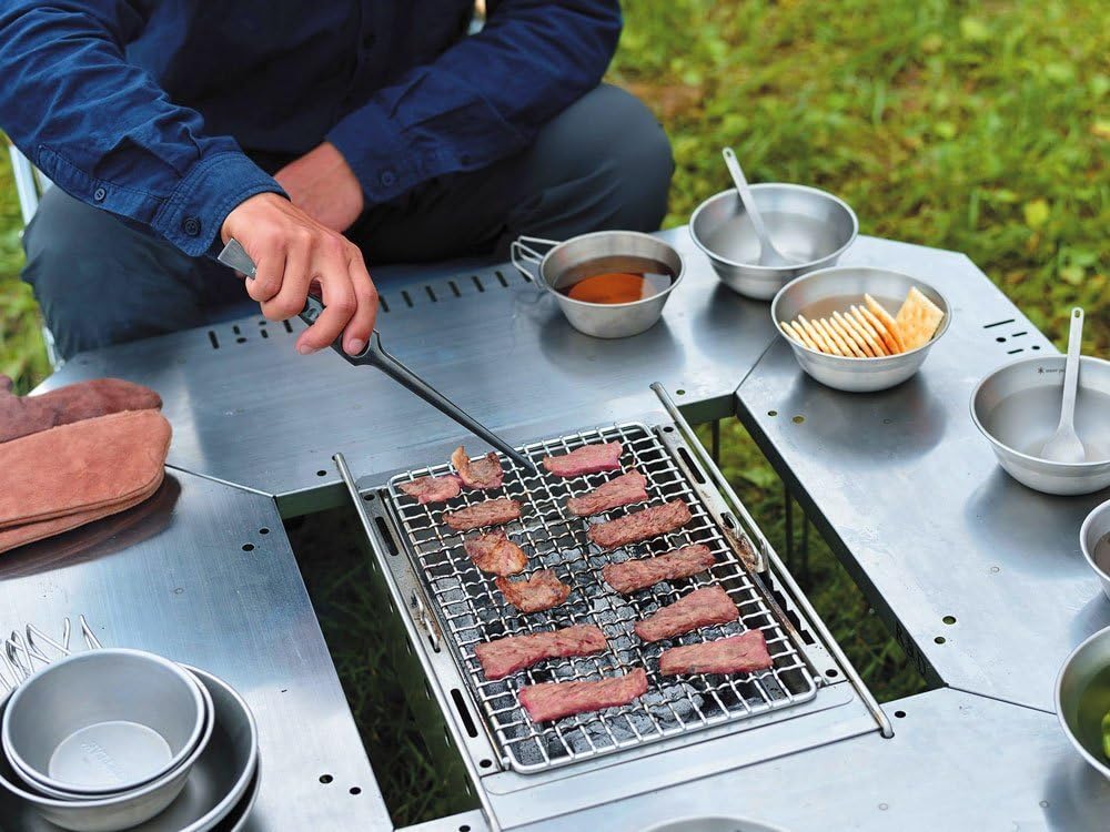 People grilling meat on a fire pit integrated into the Jikaro Table.