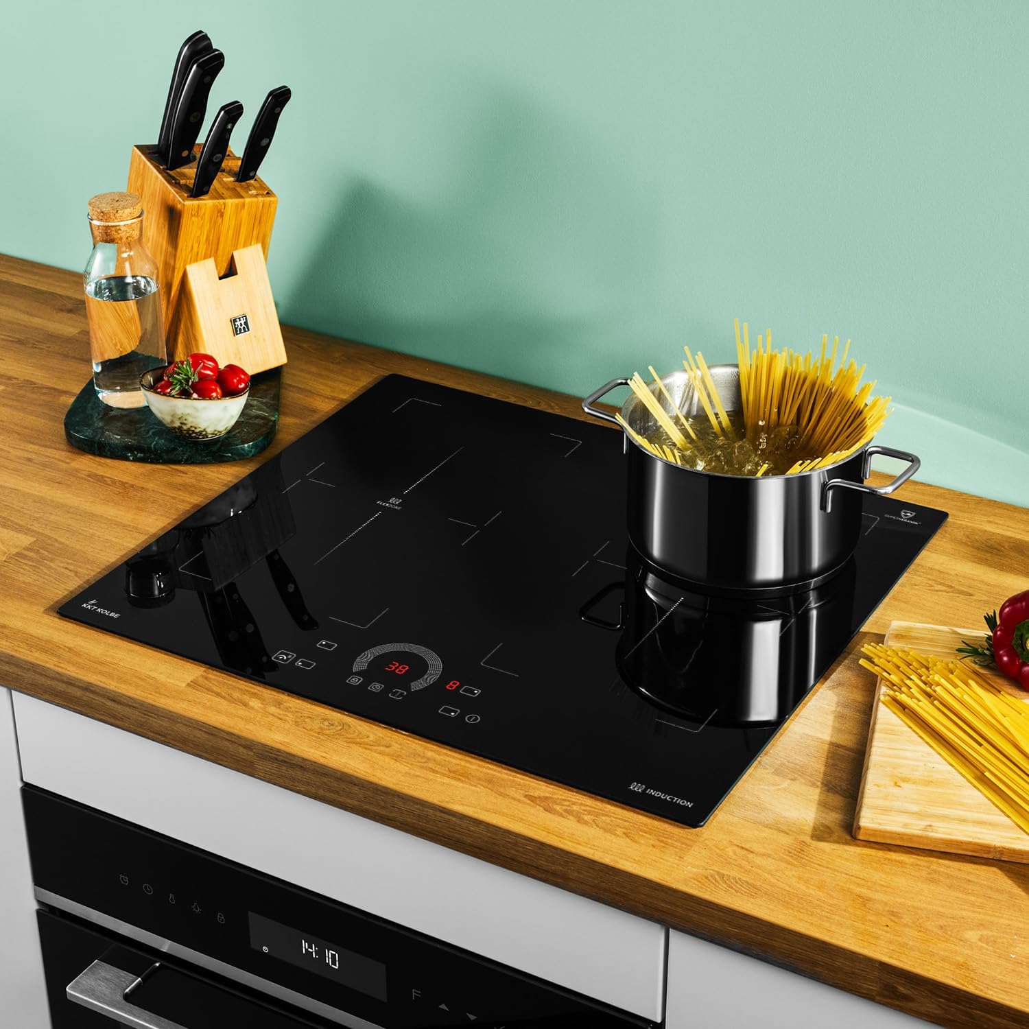 KKT KOLBE IH85904FZ Induction Hob in use, boiling pasta in a pot on the right zone, with kitchen knives and ingredients on the counter.