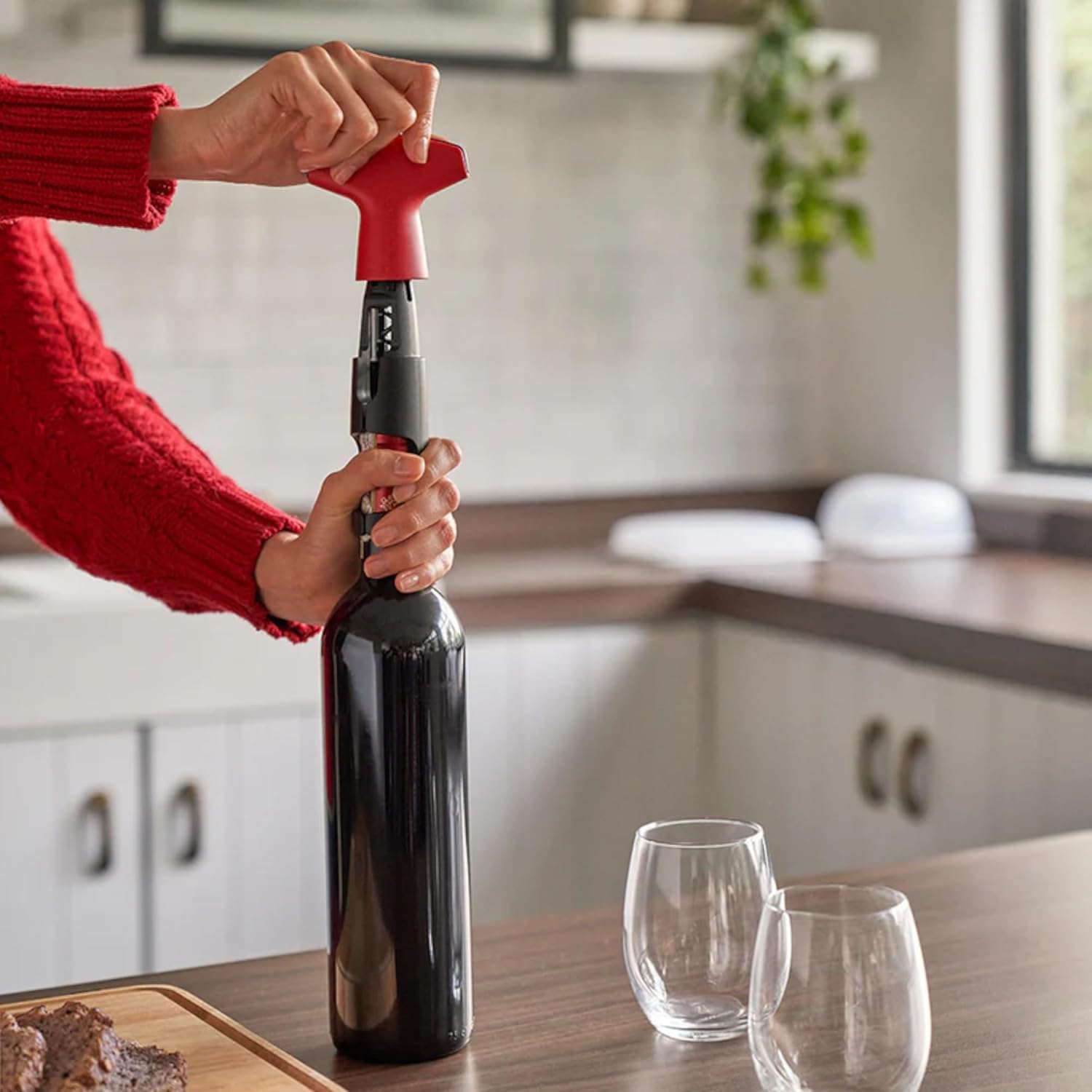 Hands turning the handle of the Tupperware Corkscrew D144 to insert the spiral into the cork.
