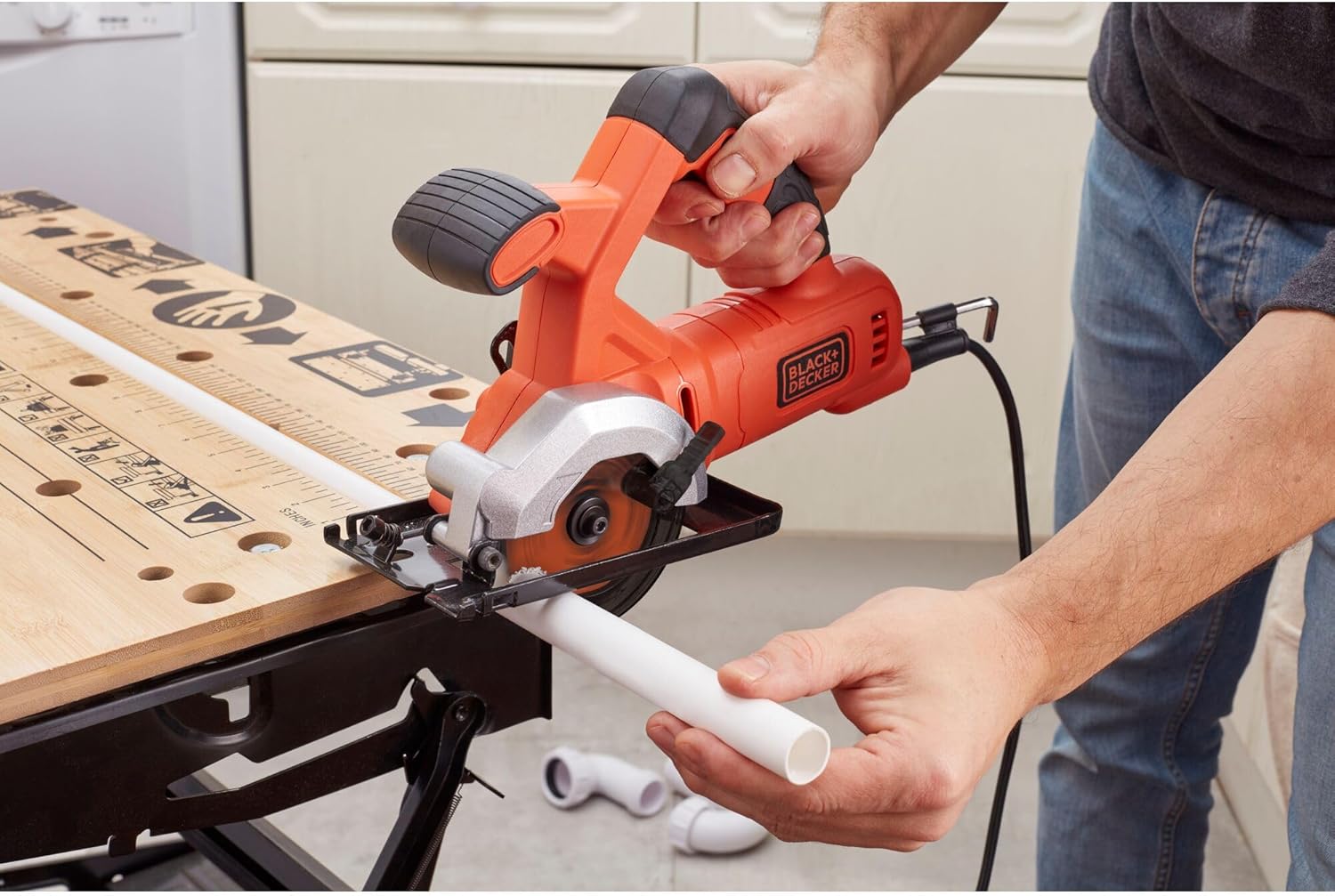 User cutting a PVC pipe with the BLACK+DECKER BES510-QS Mini Circular Saw