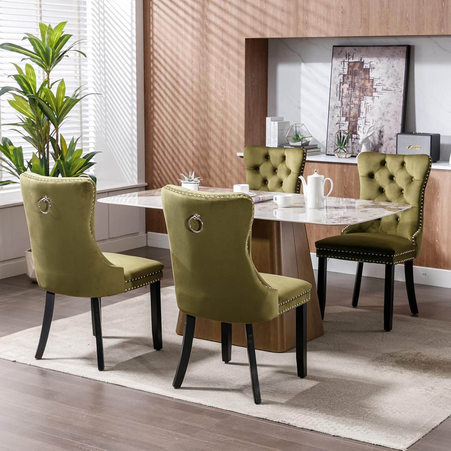 Four olive green velvet dining chairs arranged around a dining table in a modern dining room setting.