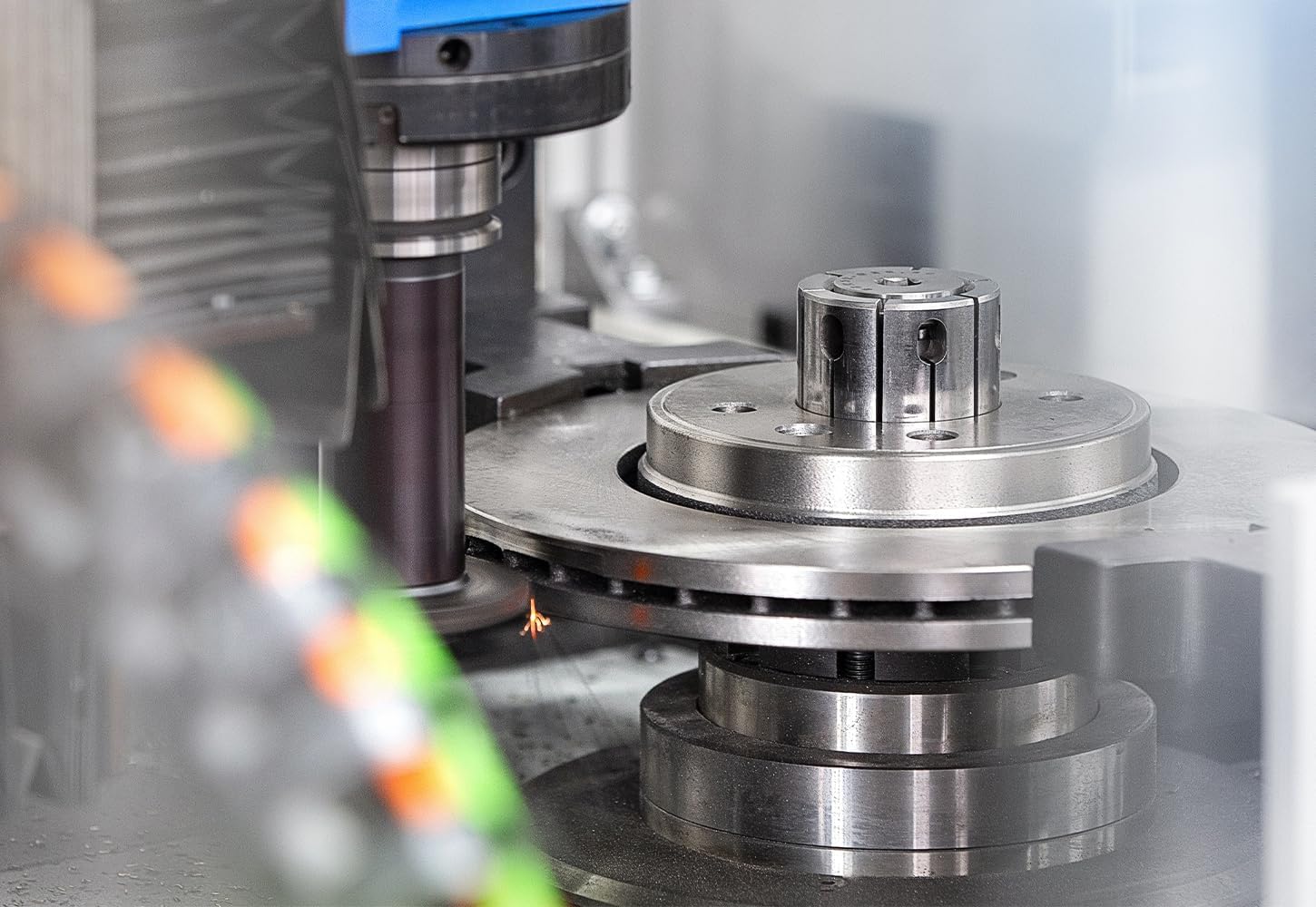 Close-up of a ROTINGER brake disc rotor undergoing precision machining in a factory setting.