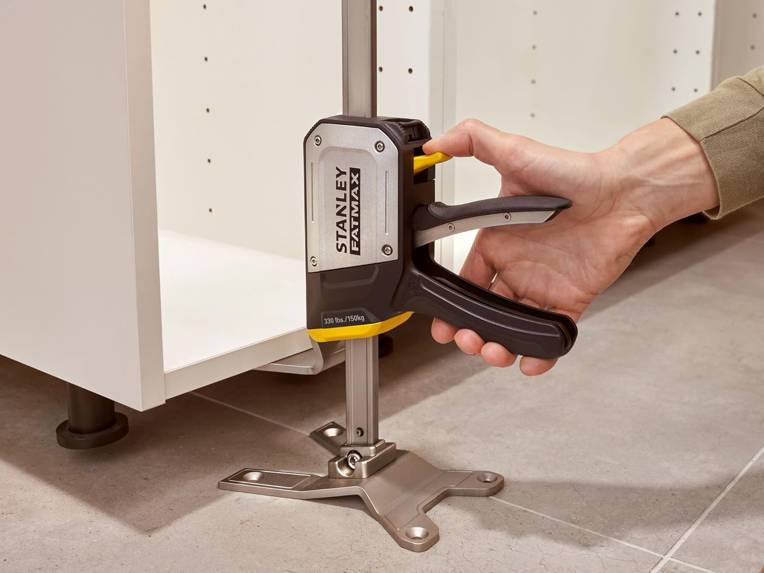 A person using the STANLEY FATMAX TradeLift to lift a cabinet during installation.