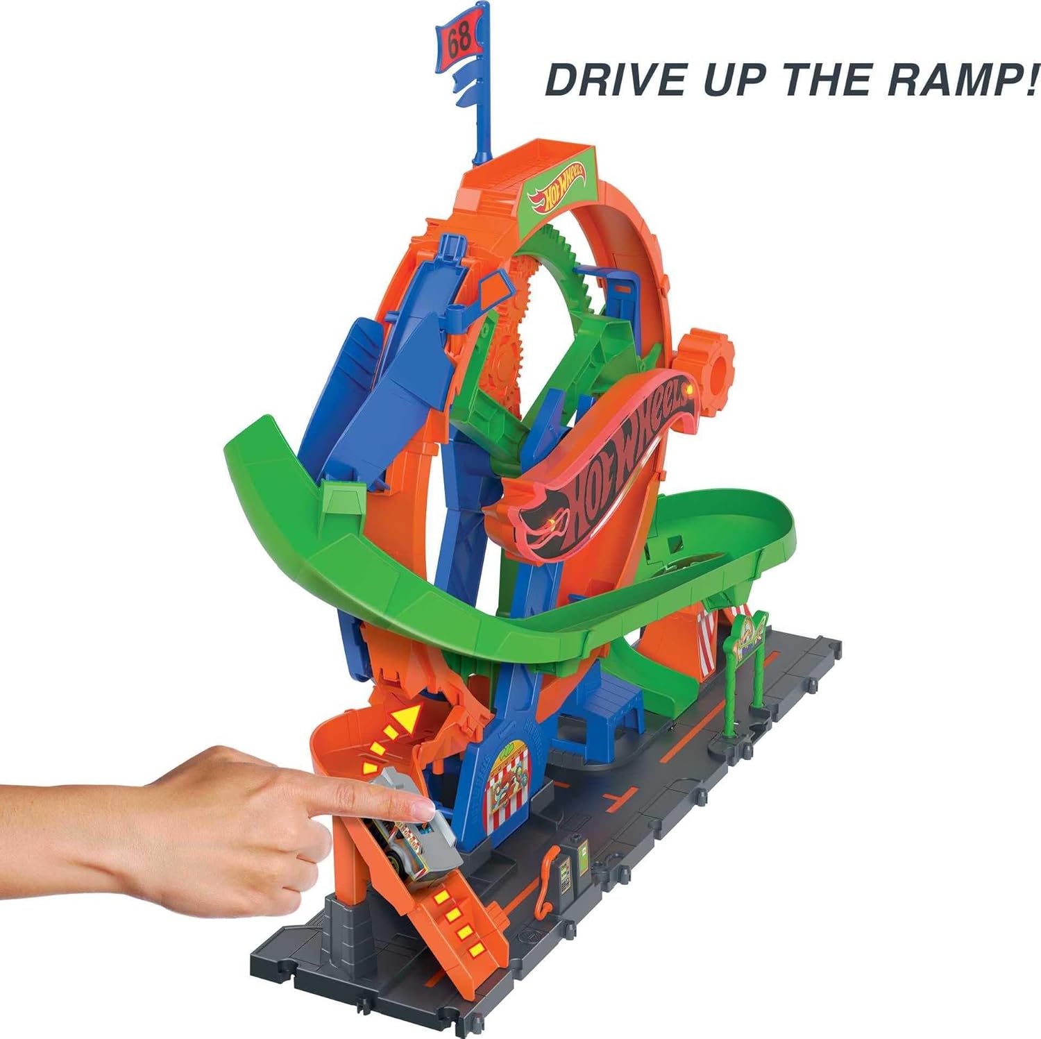 A hand pushing a Hot Wheels car up the orange entrance ramp of the Ferris Wheel Whirl playset.
