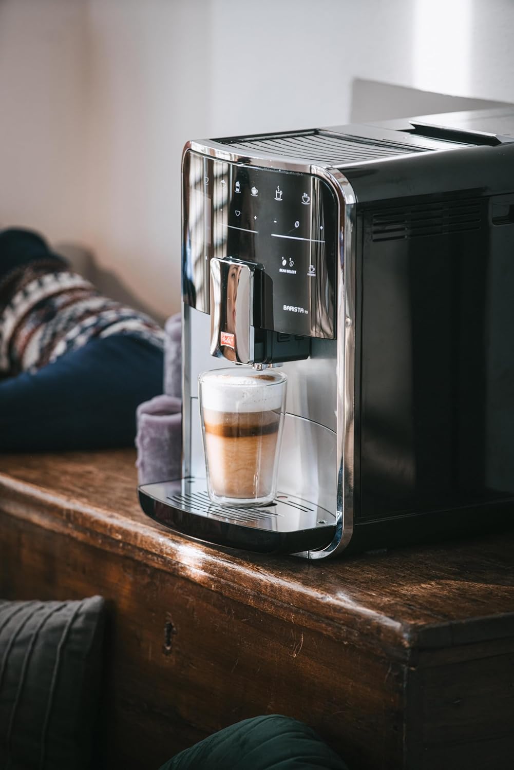 A glass of layered latte macchiato being dispensed from the Melitta Barista TS Smart coffee machine.