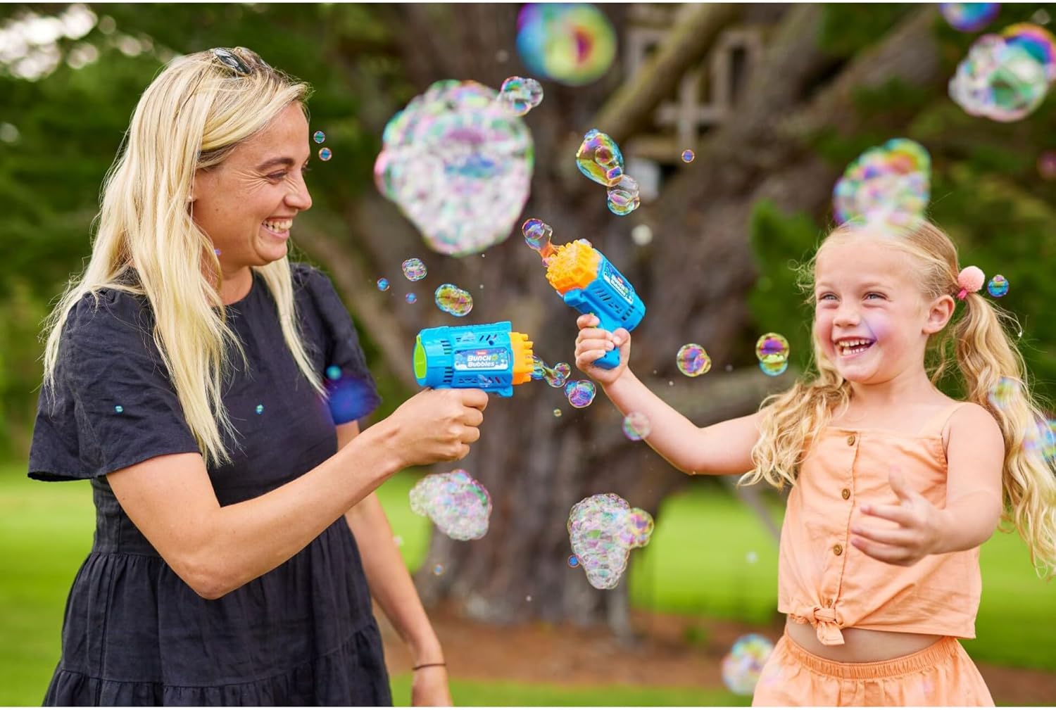 A person holding the ZURU Bunch O Bubbles Mini Bubble Blaster, which is actively producing a large quantity of bubbles.