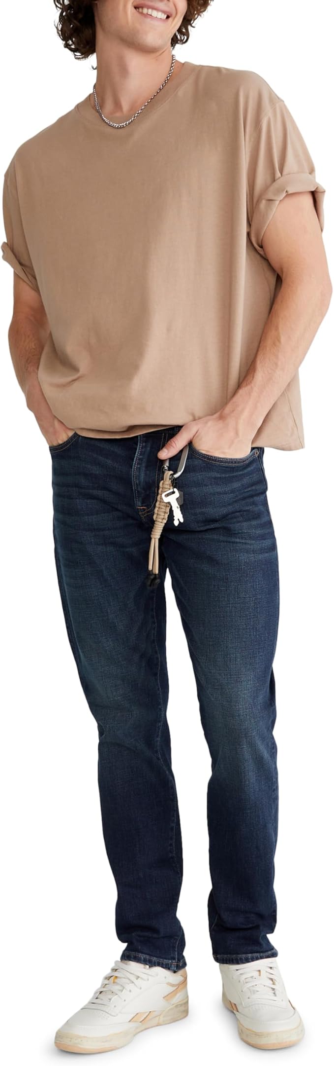 Homem vestindo calça jeans slim da Aeropostale com camiseta bege e tênis