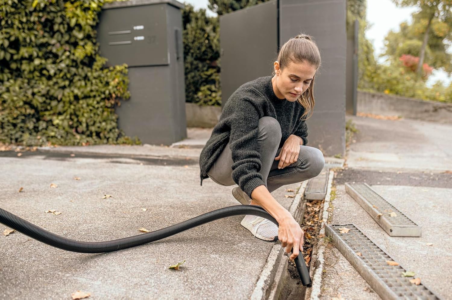 Person using the blowing function to clear debris from an outdoor drain
