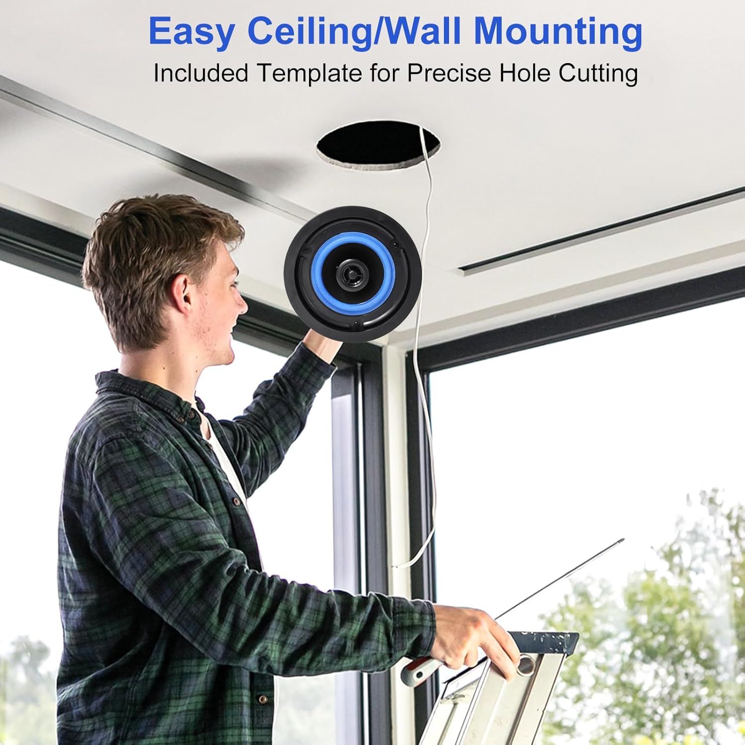 Person installing a STUDIOFINIX ceiling speaker into a pre-cut hole in the ceiling.