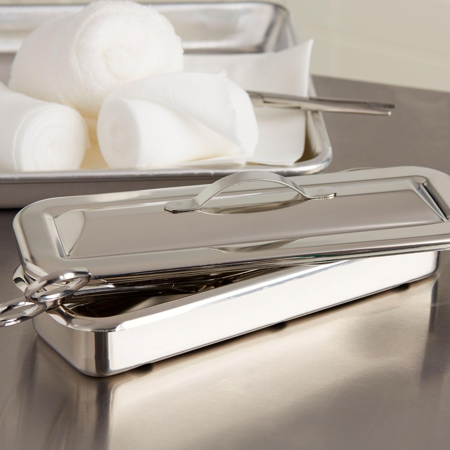 İçinde aletler bulunan ve kapağı açık McKesson marka paslanmaz çelik cerrahi alet tepsisi.